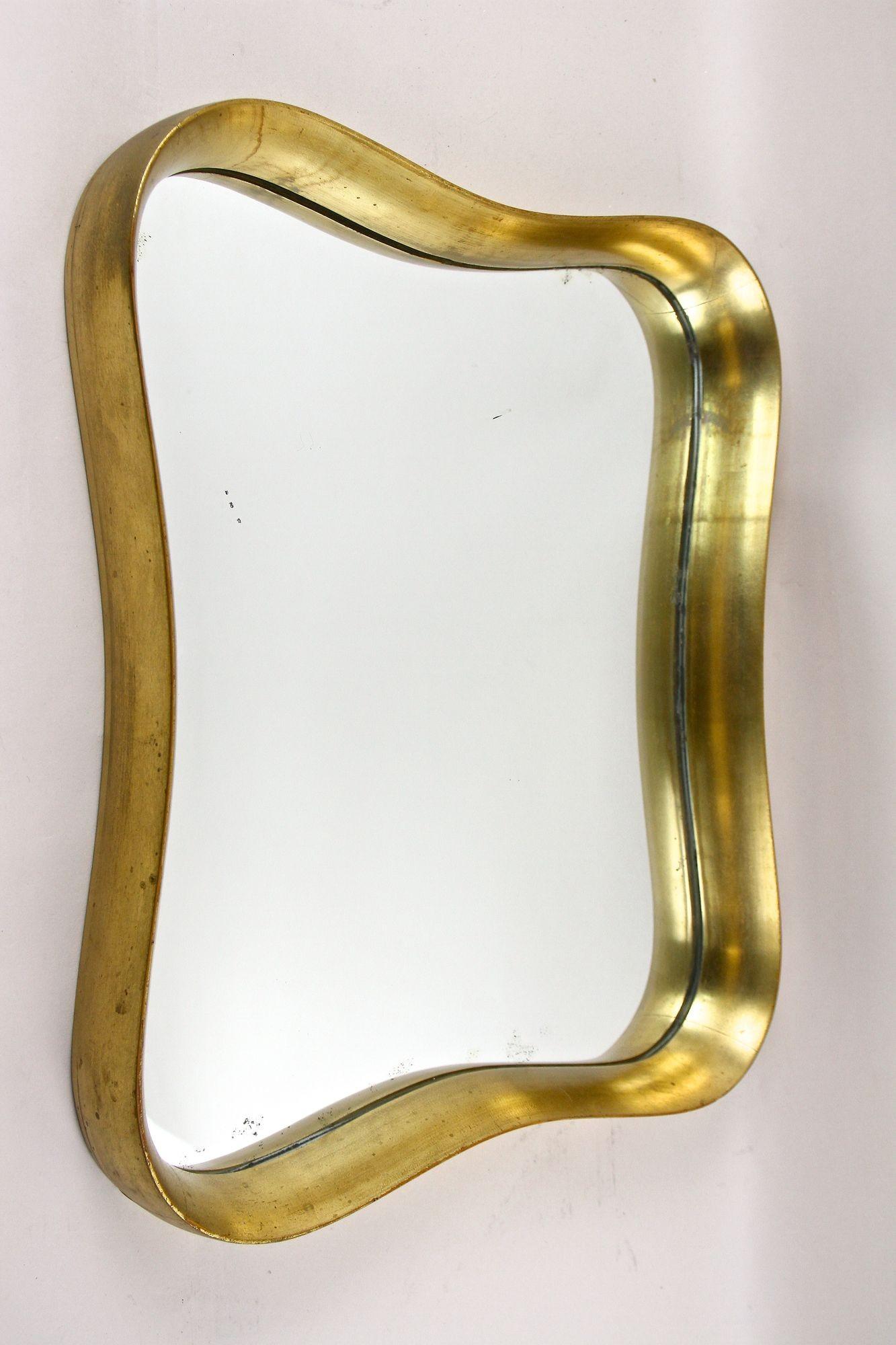 Magnifique miroir mural moderniste doré du milieu du siècle - attribué à Max Welz - datant des années 1940 à Vienne/Autriche. Le cadre en bois profond, élaboré, impressionne par ses lignes élégamment incurvées et sa surface dorée brillante,