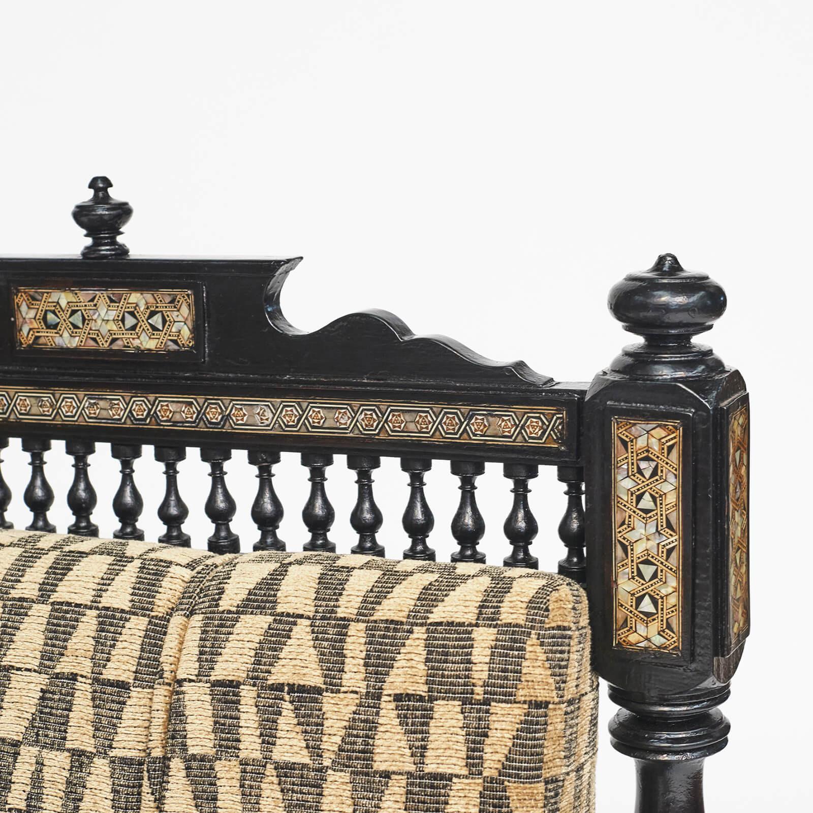 A Moroccan ebonized,  bone and semi precious stones armchair
Approx. 1900. 
Upholstered drop-in seat and back cushion, turned back supports and legs, lattice style carved arm panels.

New upholstery Fabric from  Larsen.