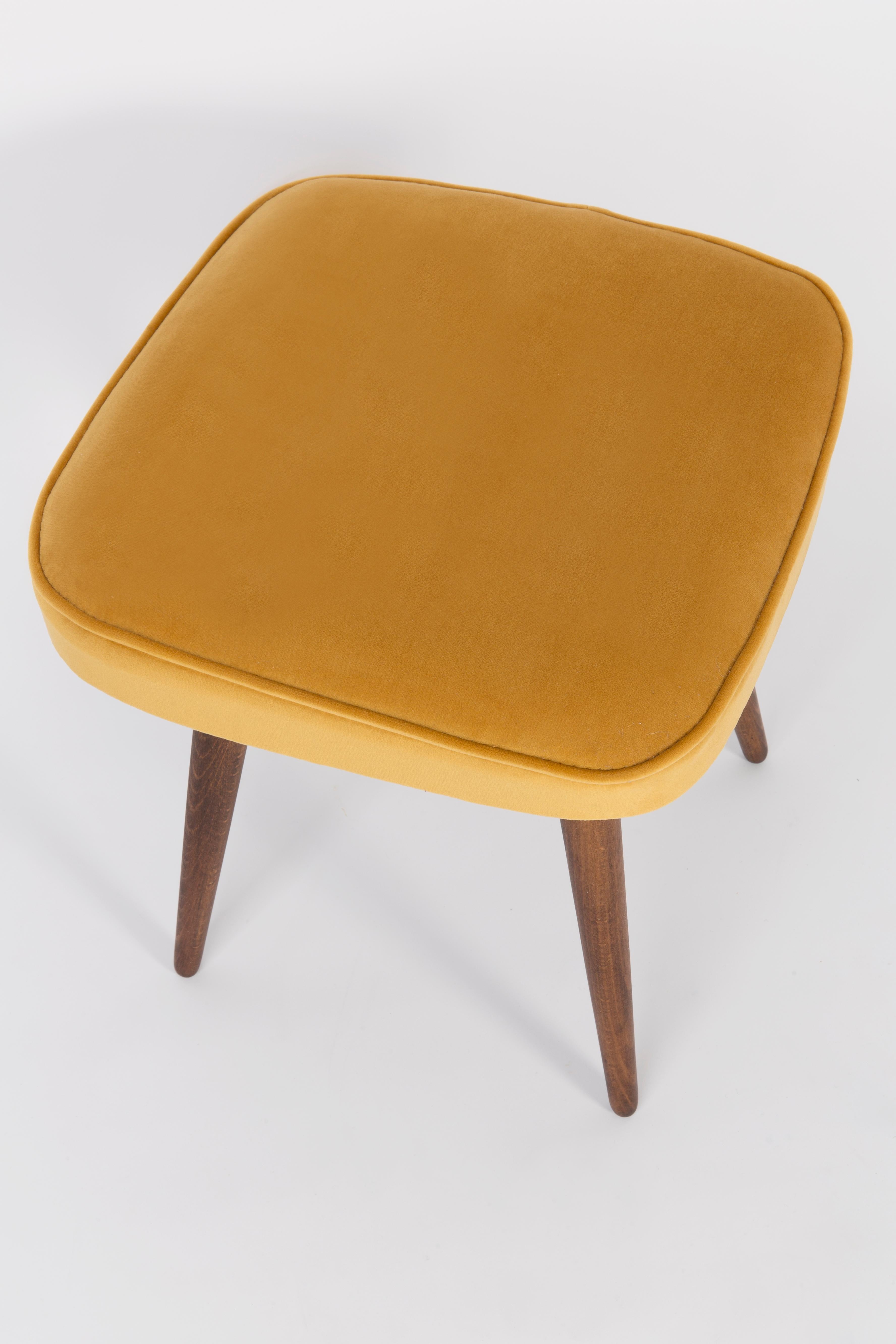 Tabouret du tournant des années 1960 et 1970. Magnifique revêtement en velours moutarde. Le tabouret se compose d'une partie rembourrée, d'une assise et de pieds en bois rétrécissant vers le bas, caractéristiques du style des années 1960. Nous
