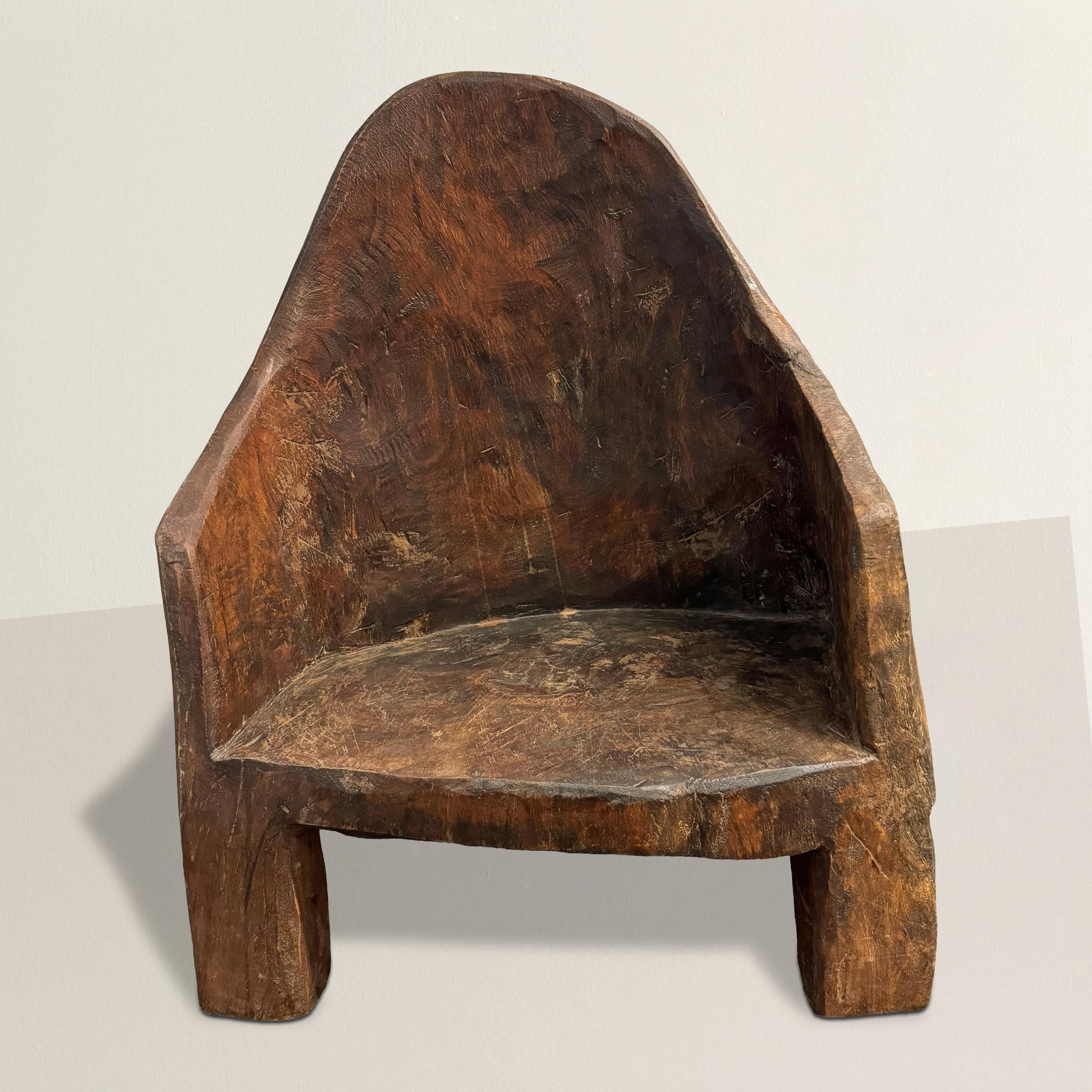 This 20th-century chair, hand-carved from a single piece of wood by the Naga people of India, is a remarkable blend of primitive charm and modern spirit. The Naga people, known for their rich cultural heritage and skilled craftsmanship, have created
