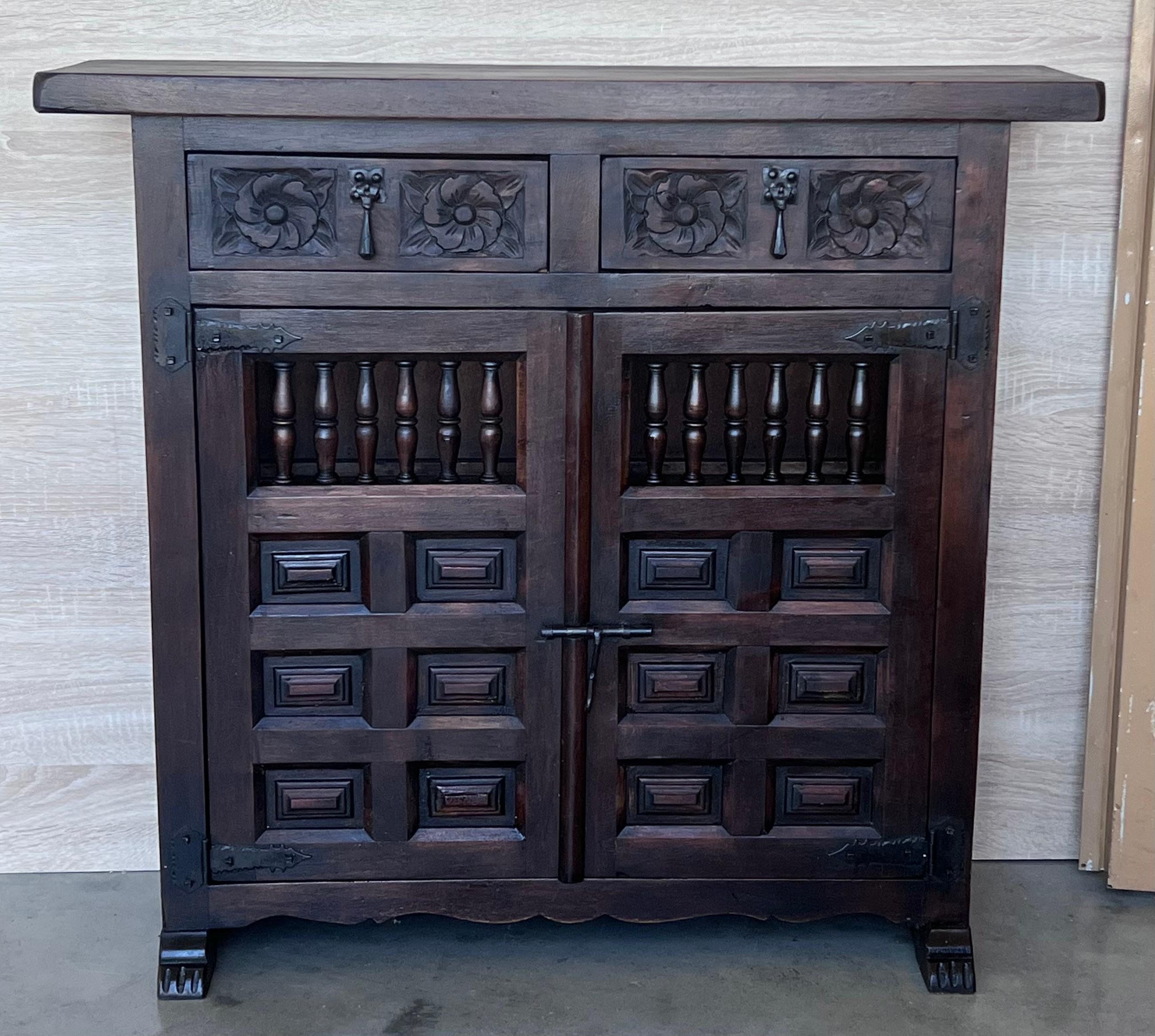 From Spain, constructed of solid walnut, the rectangular top without edge top, conforming case housing two carved drawers with floral motifs and two doors paneled with solid walnut, raised on a plinth base.
Very heavy and original cabinet.

WE