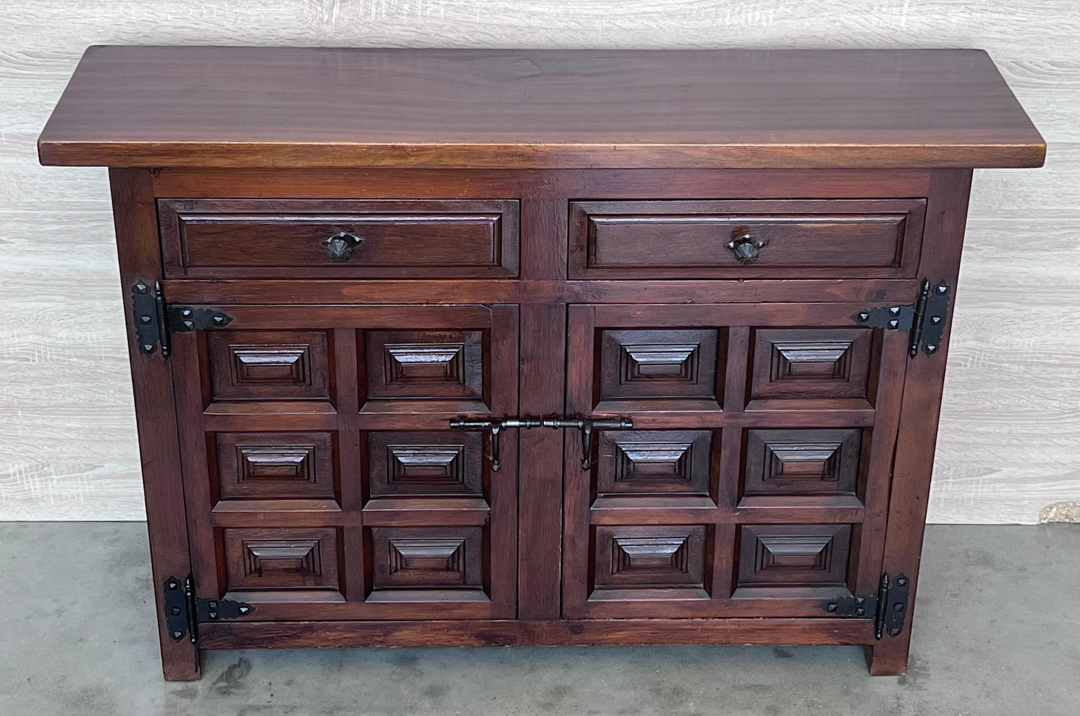 From Spain, constructed of solid walnut, the rectangular top without edge top, conforming case housing two carved drawers with two doors paneled with solid walnut, raised on a plinth base.
Very heavy and original cabinet.

WE WILL RESTORE THE