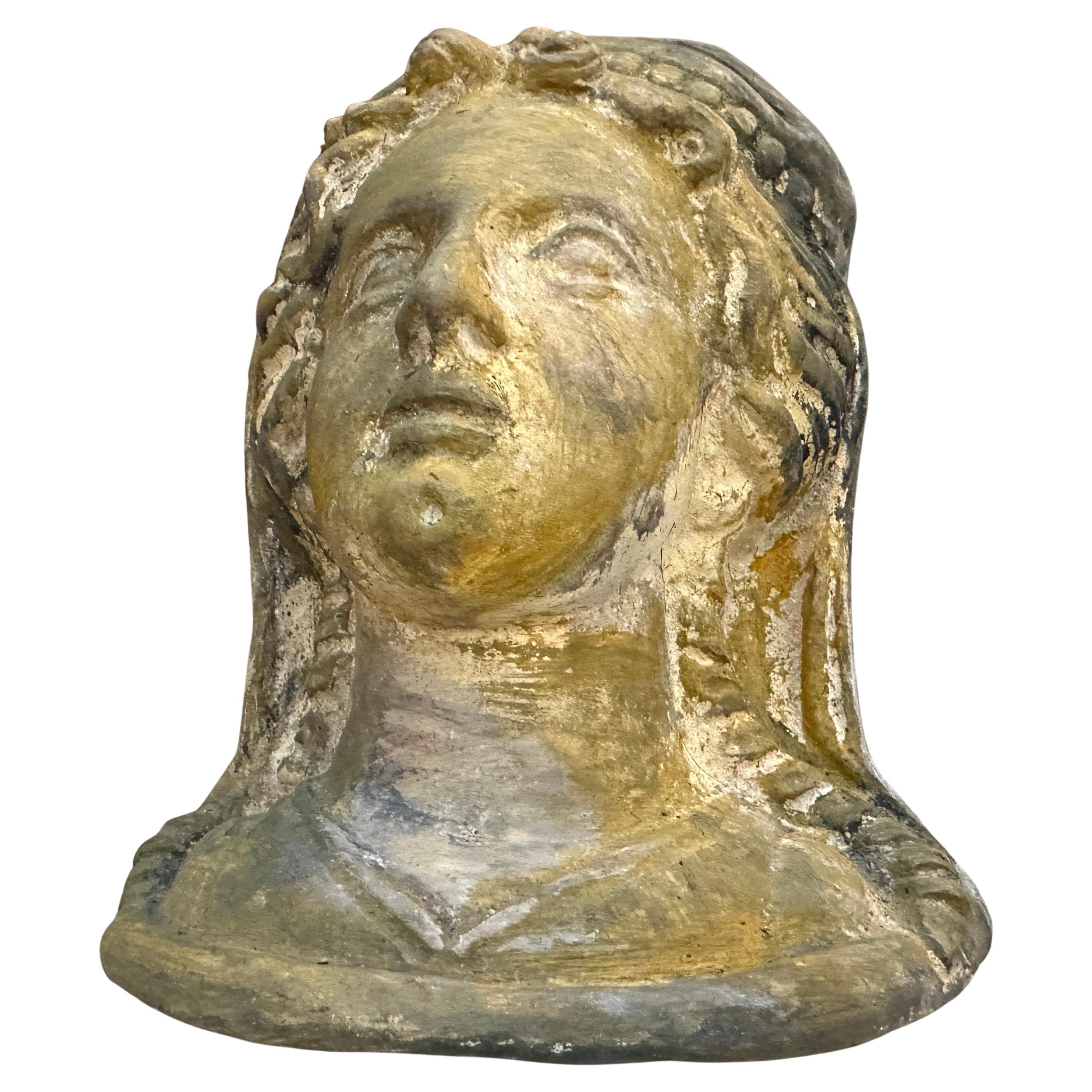 Il s'agit d'une sculpture en forme de buste, qui représente la tête d'une femme aux traits doux et classiques. Le visage présente des traits sereins, quelque peu idéalisés, avec une bouche fermée ou neutre et des yeux lourds, ce qui lui confère une