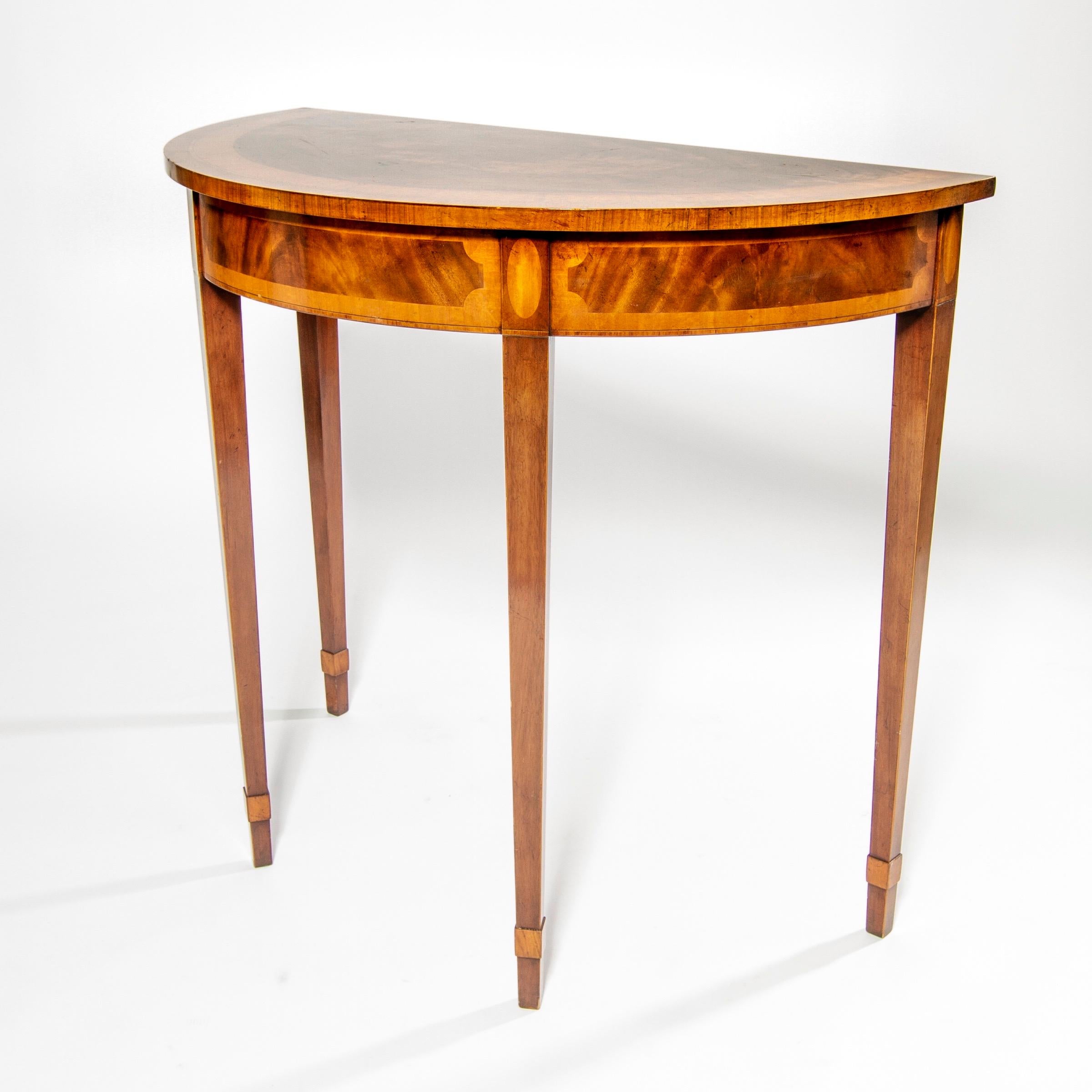 Beautiful neoclassical directoire style demi lune console table rendered in mahogany with exquisite inlay marquetry of maple and burl elm, by RBC (Restall Brown and Clennell) furniture of England.