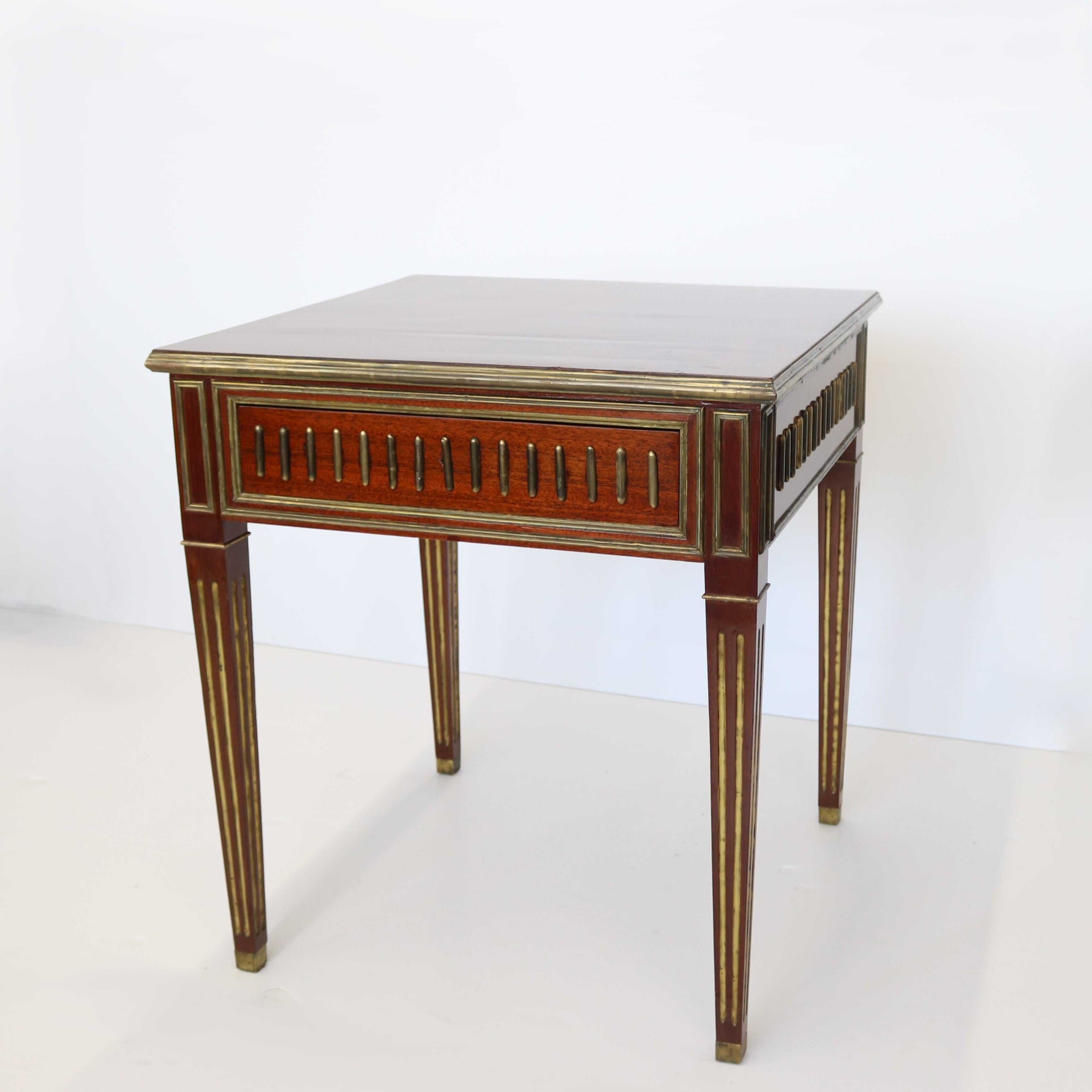 Une belle table carrée de style néoclassique. Le bois d'acajou hautement figuré est rehaussé d'incrustations en laiton patiné. Il y a également un tiroir caché. 