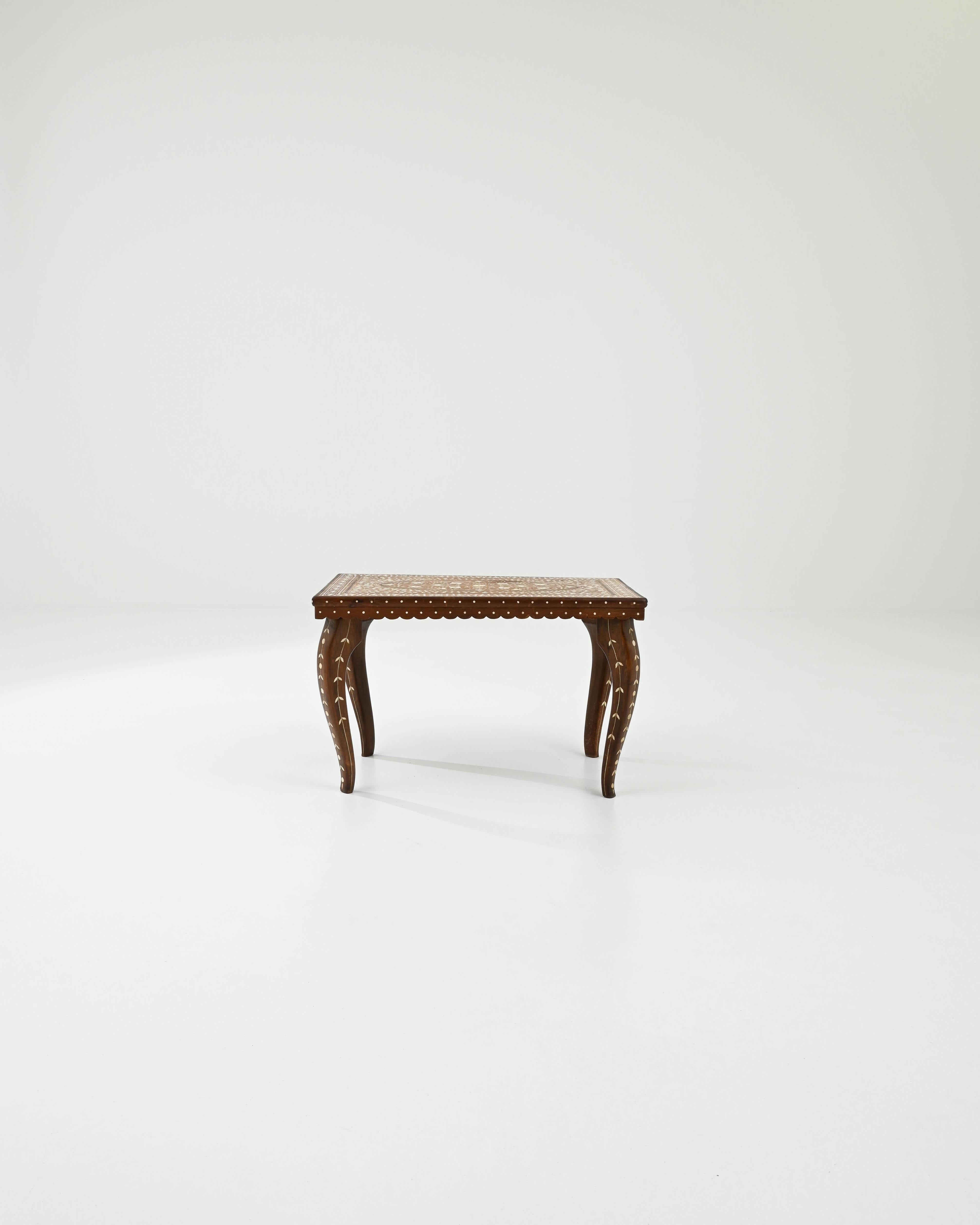 Ornate and beautifully crafted, this vintage wooden coffee table makes an endlessly mesmerizing accent. Hand-built in Africa in the 20th century, a rectangular tabletop with a scalloped apron sits atop graceful cabriole legs. Intricate patterns of