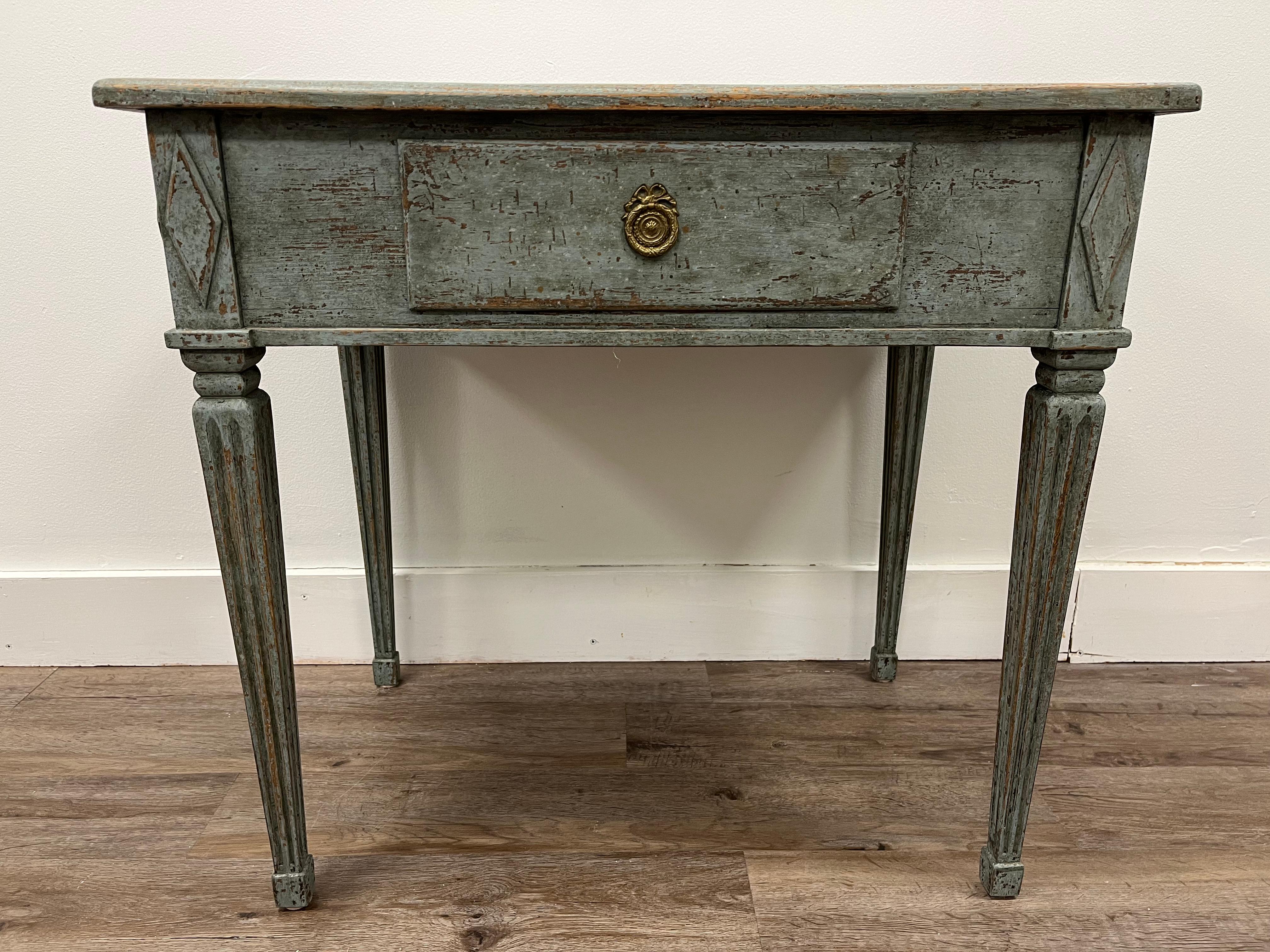 A Gustavian style table with Dutch tile top. Single drawer with original brass pull. Frame has diamond corner details. Legs are tapered and fluted. In original blue paint.
