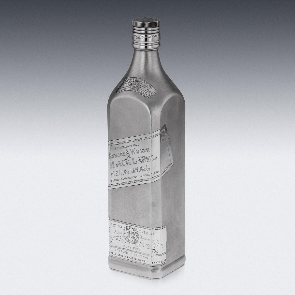 Bouteille de whisky Johnnie Walker en argent massif, de grande taille et de forte épaisseur, de forme rectangulaire avec finition givrée, gravée d'étiquettes représentant une bouteille de Johnnie Walker, avec bouchon à vis également gravé. La base