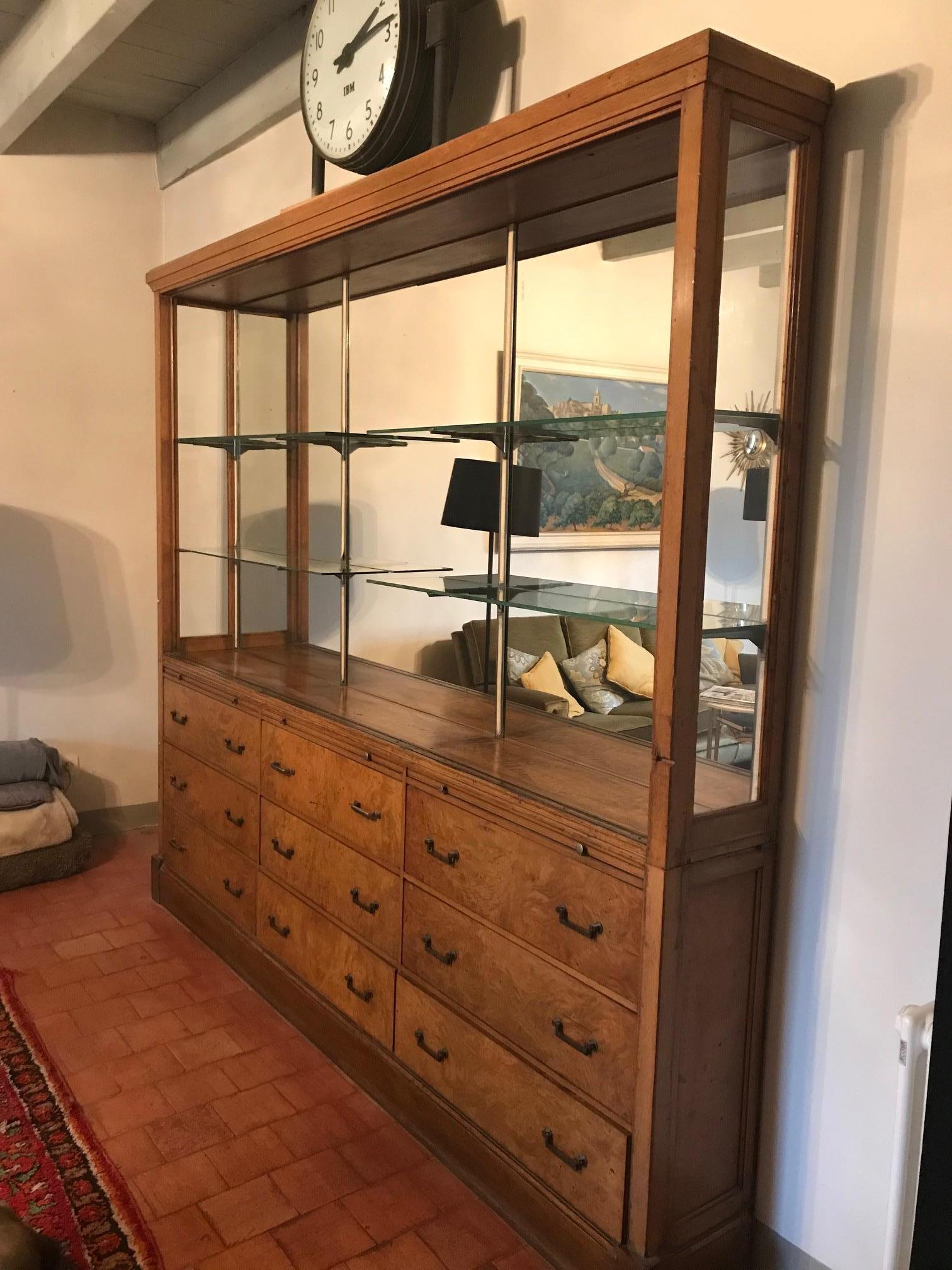 Beautiful 20th century oak and amboyna French apothecary vitrine cabinet from the 1920s.
Used to be a coffee maker cabinet. Made in two parts, large vitrine mirror in the top part with three glass shelves and nine large drawers on the bottom