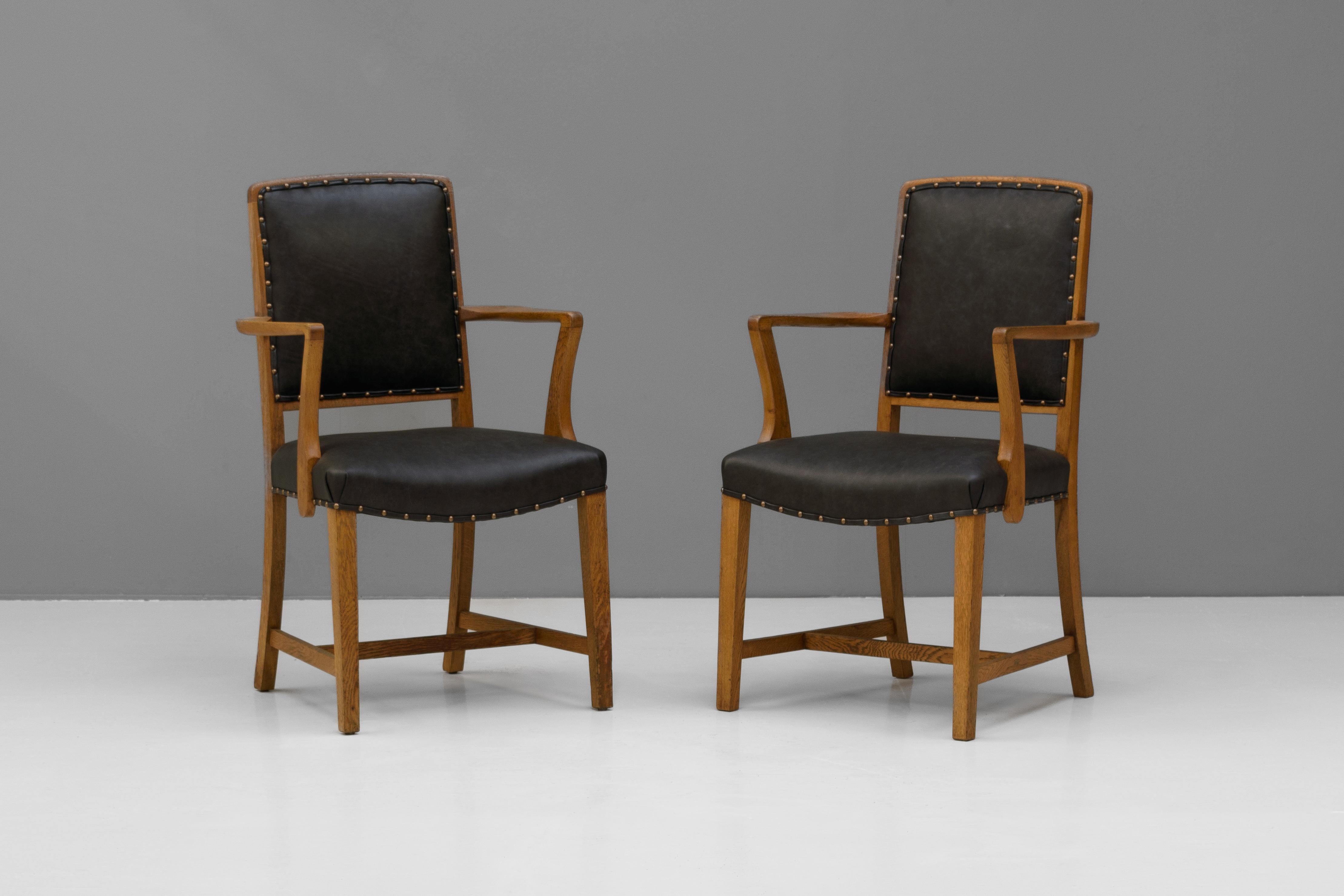 Jolie paire de fauteuils en chêne poli, recouverts de cuir noir. Circa 1930.