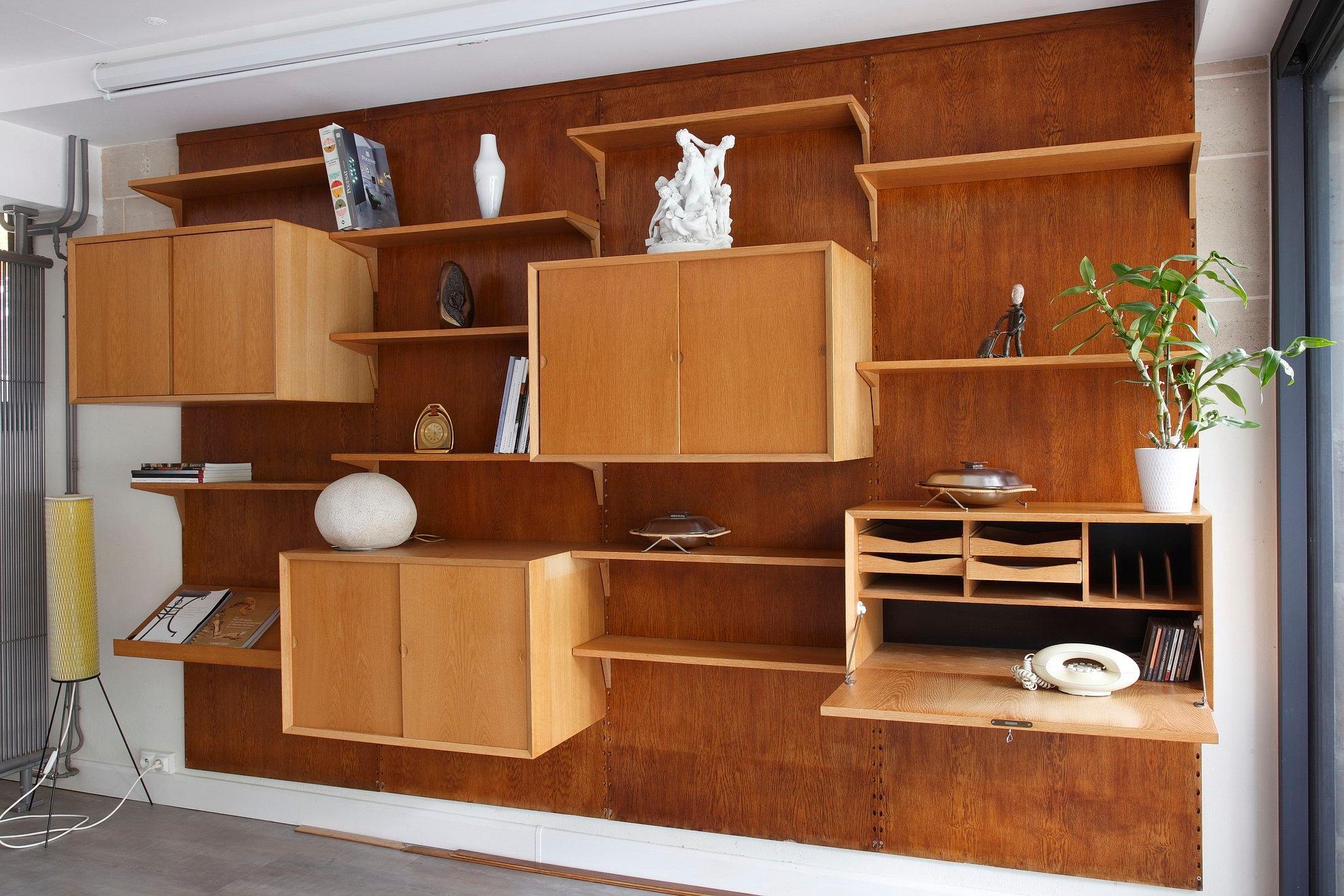 Cado wall system crafted in oak by Poul Cadovius (Denmark, 1911-2011) in the 1960s. This modular shelving system consists of four vertical panels with several shelves and cabinet units :

- 10 shelves (P: 22cm)
- 2 cabinet units with sliding