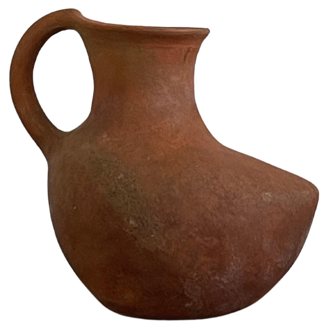 20th Century Oaxacan ceramic pitcher expertly hand crafted with a curved organic body in Mexico. Amazing piece with character in an earthy color tone. Perfect for use or display. Sturdy with no cracks and in great vintage condition.

