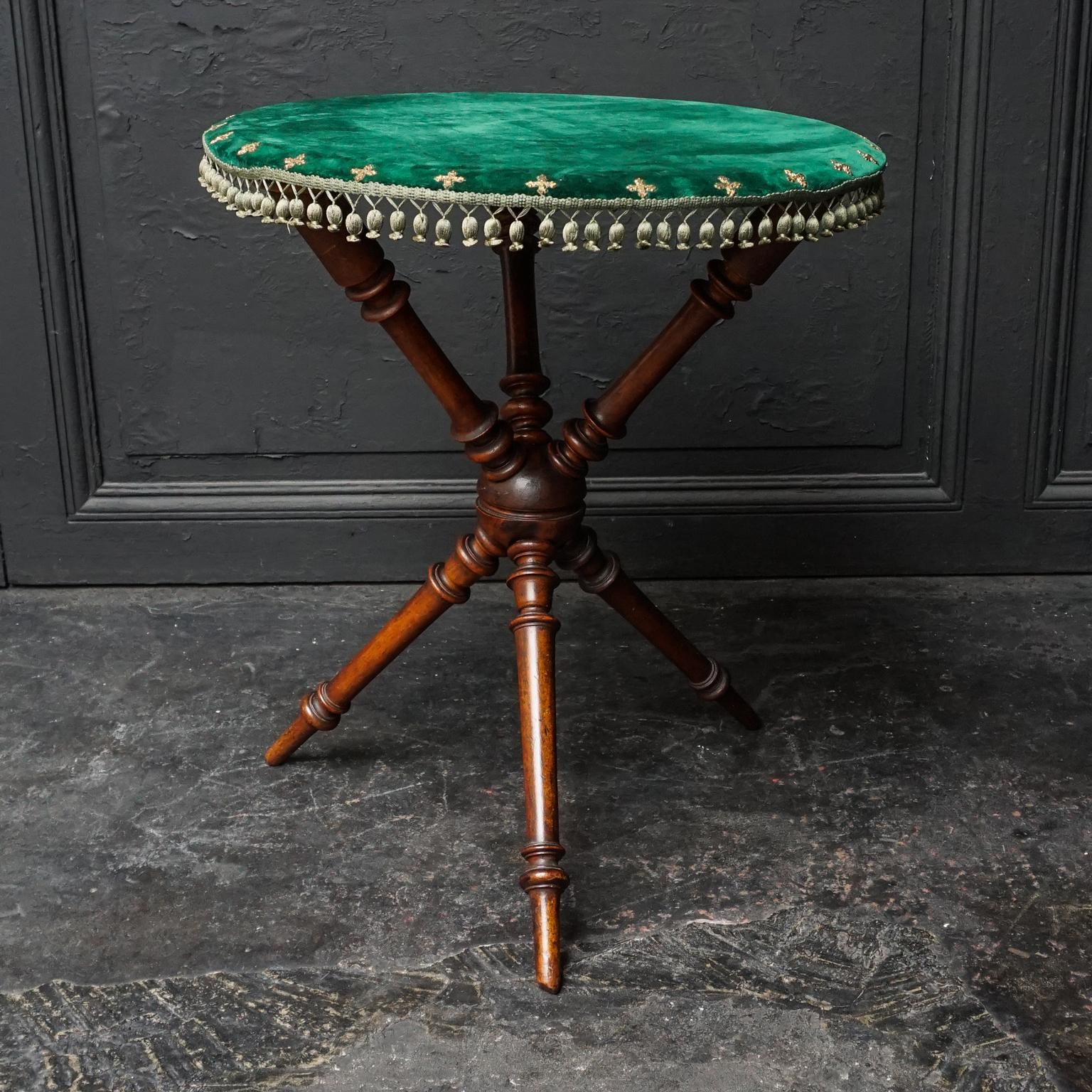 20th century occasional bobbin turned tripod mahogany table with green velvet top decorated with green tasseled band and gilt brass crosses.
The tripod legs are shaped in a Classic X-joint at the bottom. 

This little Gypsy Victorian-style table