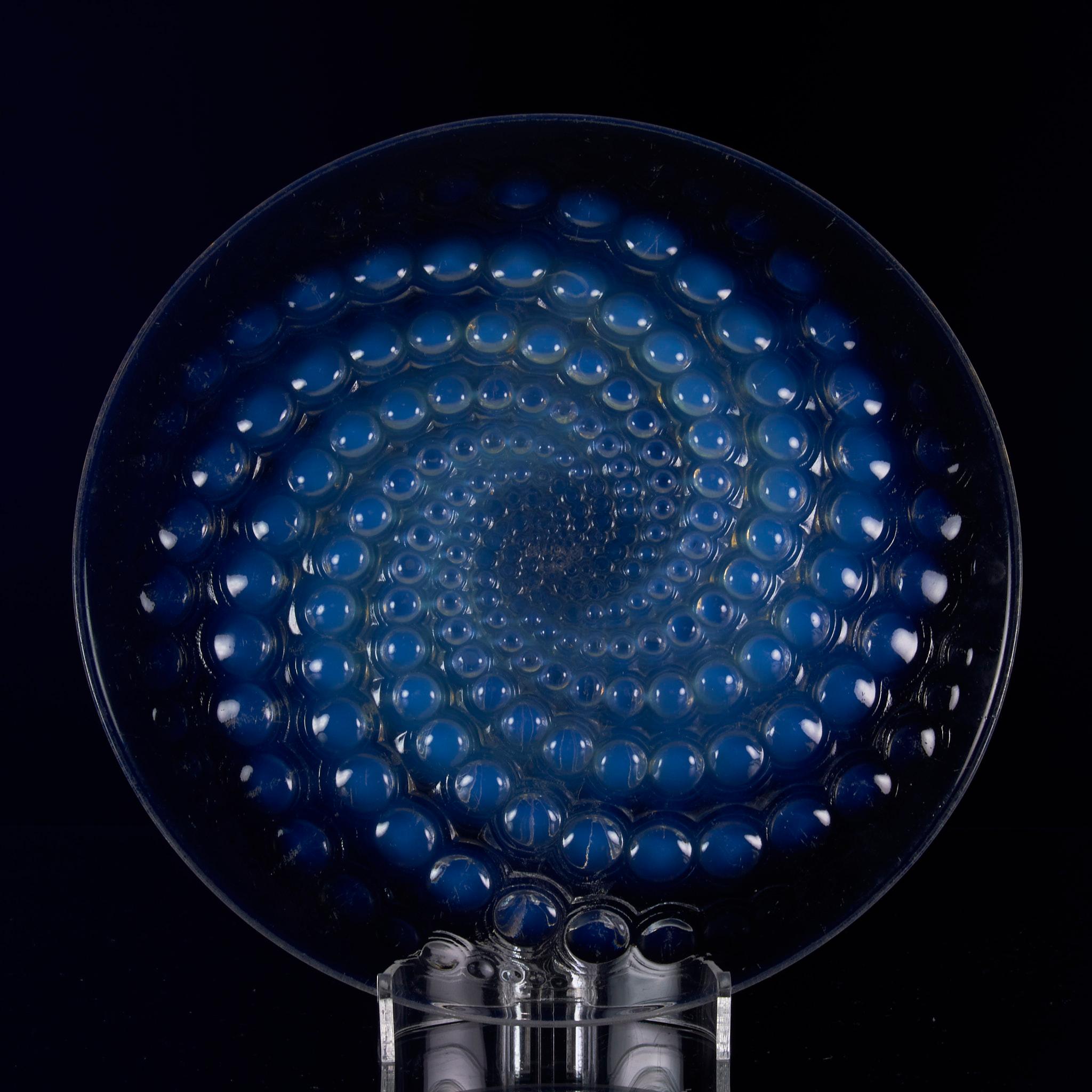 A striking early 20th Century Art Deco French clear glass plate decorated with a swirling bubbles pattern exhibiting excellent sky blue opalescent colour and fine hand chased detail, signed R Lalique France
 
‘Volutes’

Catalogue Number:
