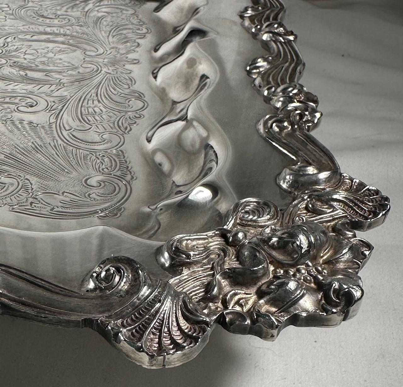 20th Century Ornate Square Footed Silver Plate Serving Tray.

	This tray is created in beautifully detailed scrollwork against a mottled background and offset by a highly ornate scroll border surrounded by a plain central cartouche. The decorative