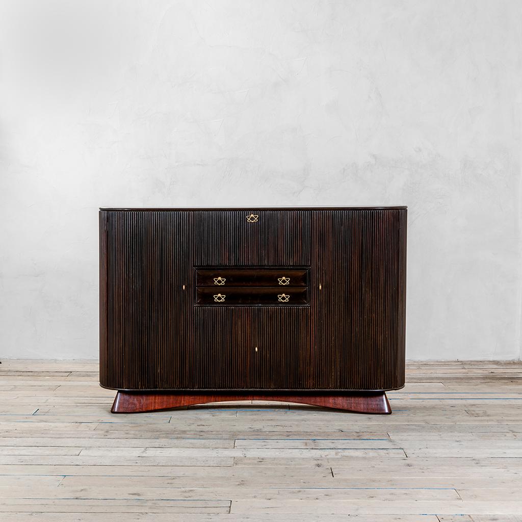 Large cabinet designed by Osvaldo Borsani in 1945. The sideboard is fully in dark wood with a special decoration in wooden slats. The Cabinet could be opened with very peculiar brass handles, and in its inside there are drawers of different sizes