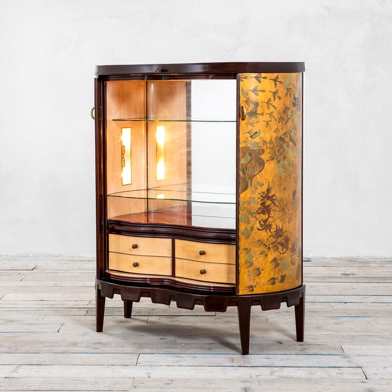 Very special bar cabinet made in the mid-40s by the magical atelier of Osvaldo Borsani. 
The bar cabinet is made of wood and painted wood, superbly decorated with musician angels and vegetation. Its two curved doors slide and open a lighted