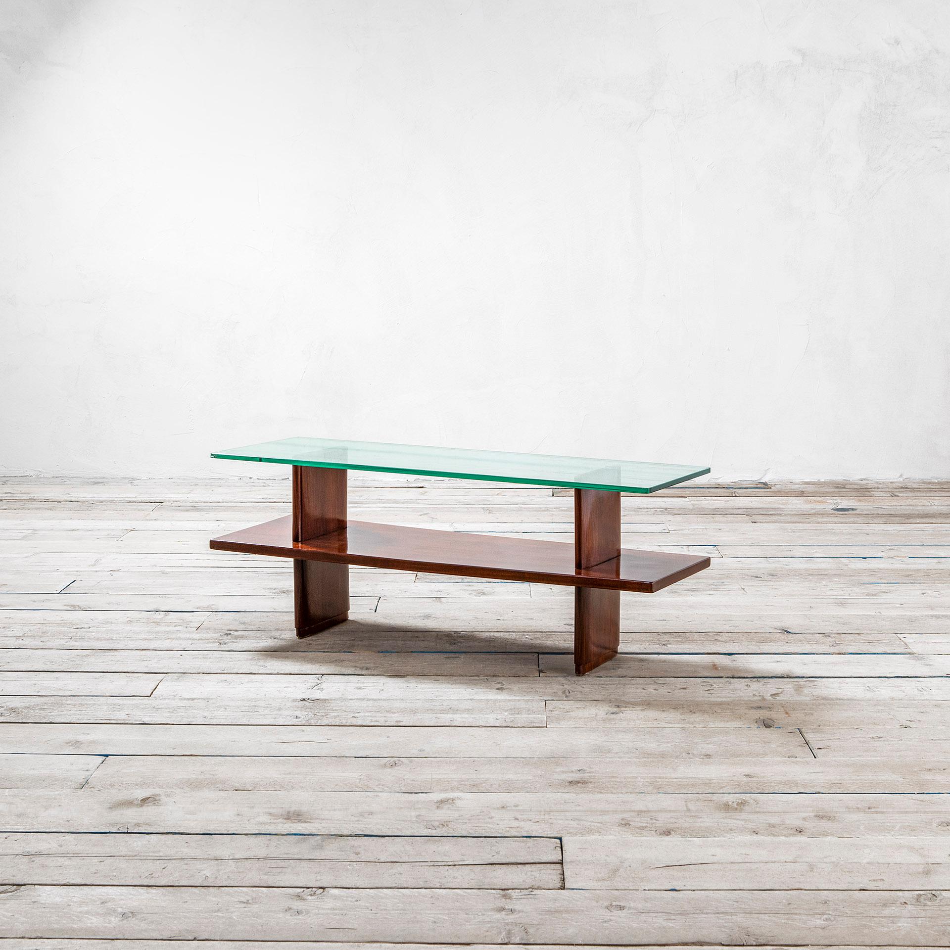 Couchtisch, entworfen von Osvaldo Borsani in den 40er Jahren. Der Tisch hat eine Holzstruktur und 2 Platten, eine aus Holz und eine aus Glas. Die Form des Tisches ist meist rechteckig, aus diesem Grund ist dieser Tisch besonders für schmale Räume