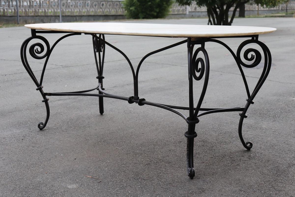 Majestic large oval garden or patio table. Made with iron base and oval Portuguese marble top. Characterized by a rich iron decoration with scrolls. The high quality marble top shows some signs of wear especially on the edges, please look at all the