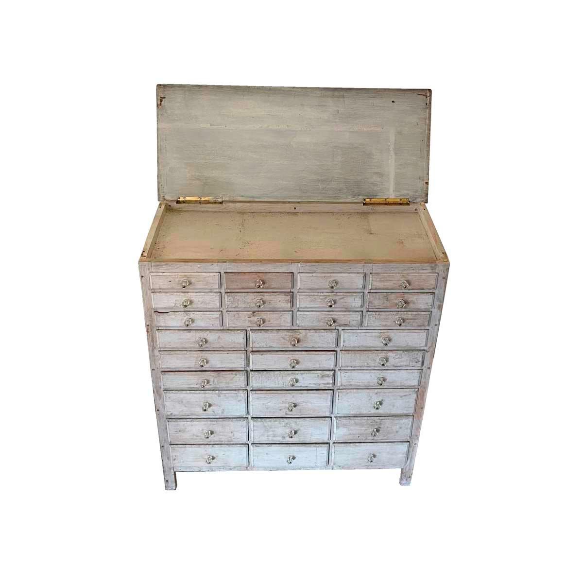 Early 20th century country apothecary or general store cabinet with 30 graduated drawers below a lift-top enclosing a shallow storage area. In original white paint, retaining it's original faceted glass drawer pulls, and having drawers with beveled