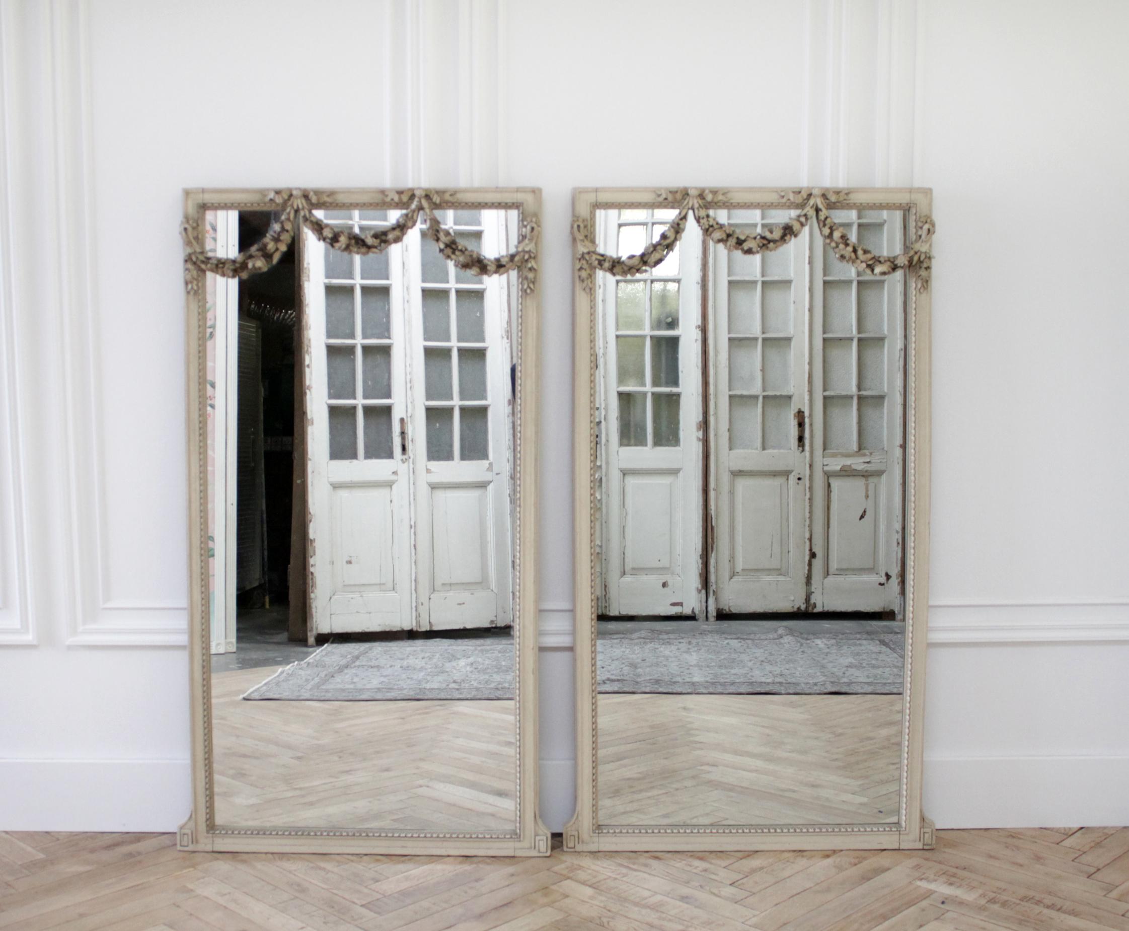 20th century painted and carved french style mirrors
Sold individually these beautiful mirrors have the original patina painted finish. A grayish-tone colored paint, with subtle distressed edges. Large carved wood rose swags scallop over the fronts