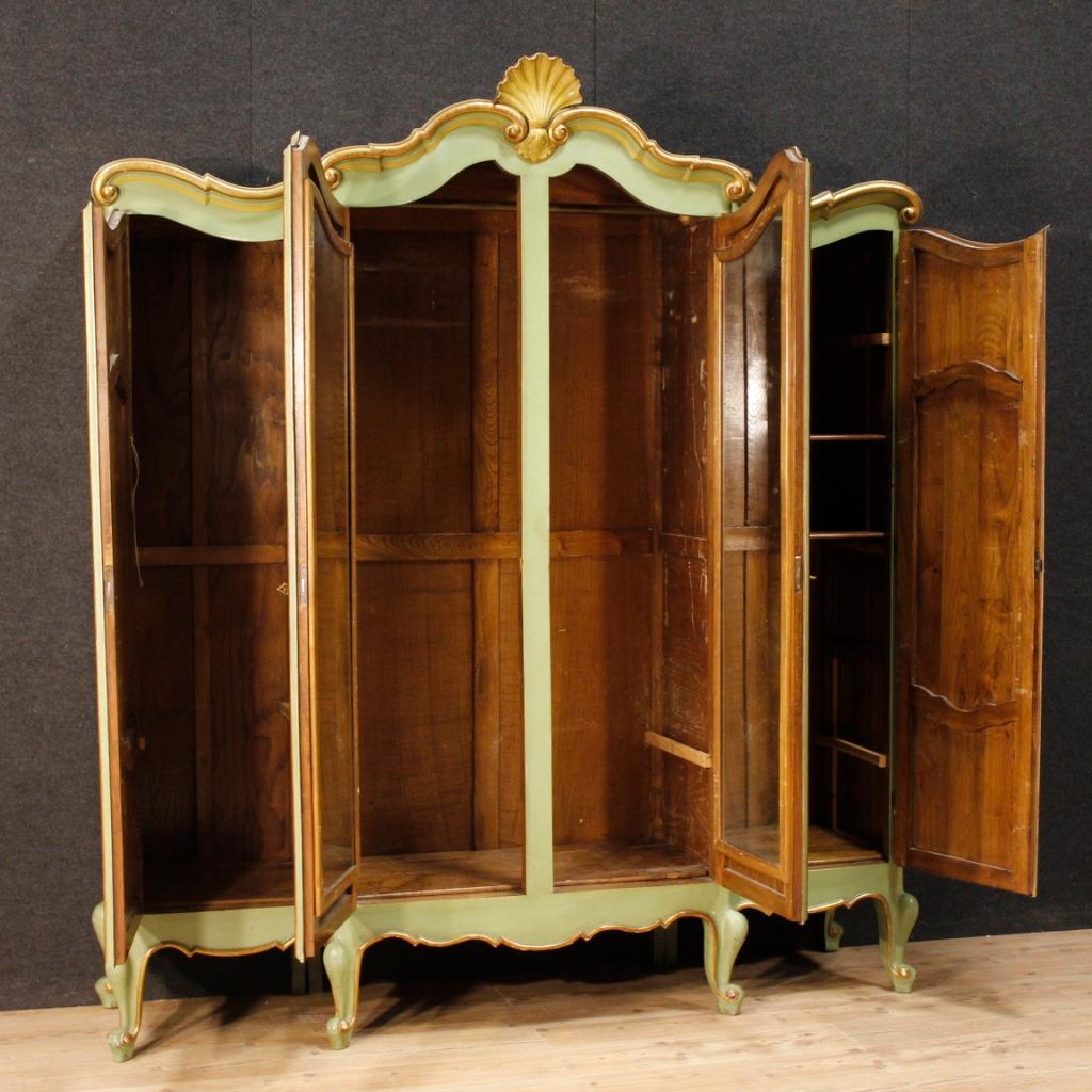 Italian wardrobe from 20th century. Pleasantly carved, gilded and hand painted wooden furniture with very pleasant floral decorations. Four doors armoire of excellent capacity and service. Completely removable furniture to facilitate movement and
