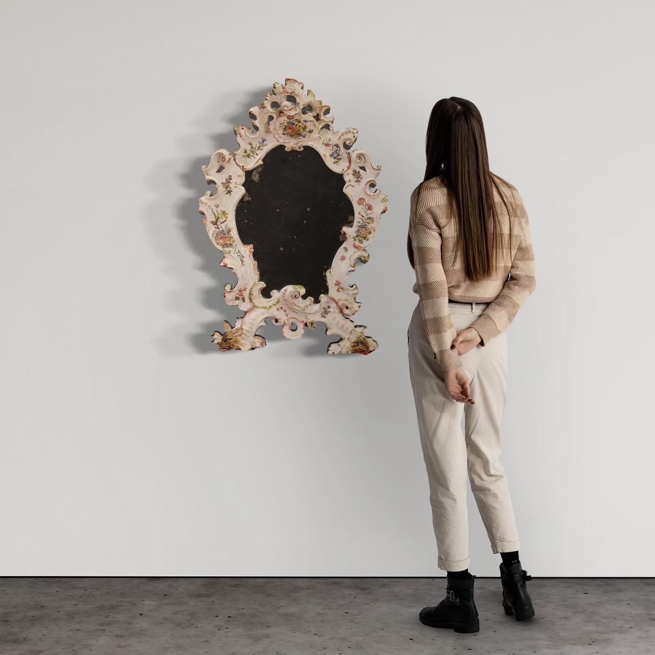 Italian mirror from the first half of the 20th century. Bassano production object in enameled and hand-painted ceramic with floral and zoomorphic decorations of excellent quality. Mirror composed of various ceramic elements fixed and applied on a