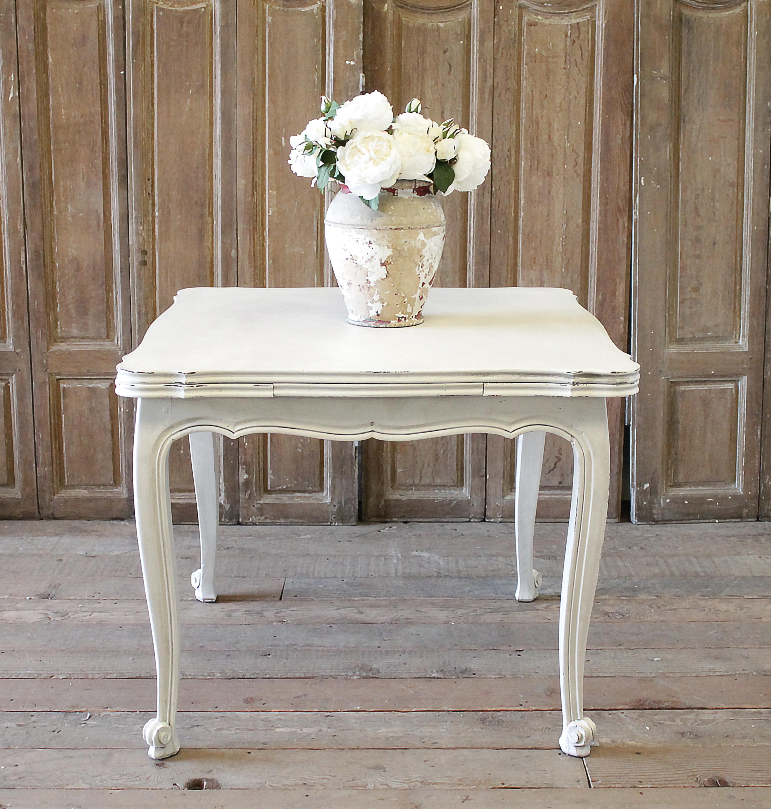 Good quality French farmhouse extending table featuring a parquetry top that can be seen on the top centre. Slight serpentine outer edge, extension leaves pull out easily from each underside of the table. Painted in a soft antique white with subtle