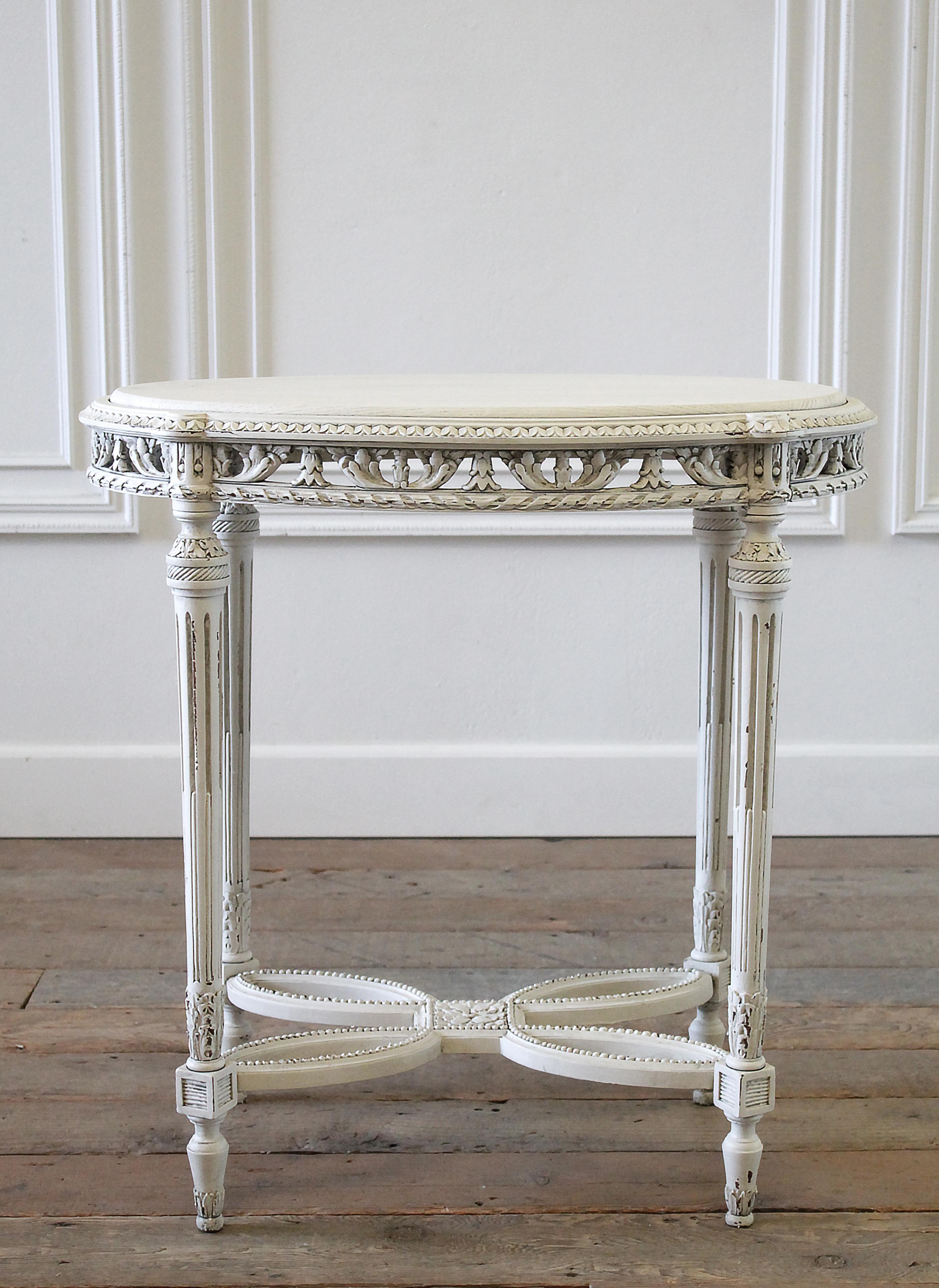 20th century painted oak carved side table in the Louis XVI style.
Painted in a soft white color, with subtle distressed edges, and finished with an antique glazed patina. Legs and base are sturdy, can be used for everyday. Fluted carved legs, with