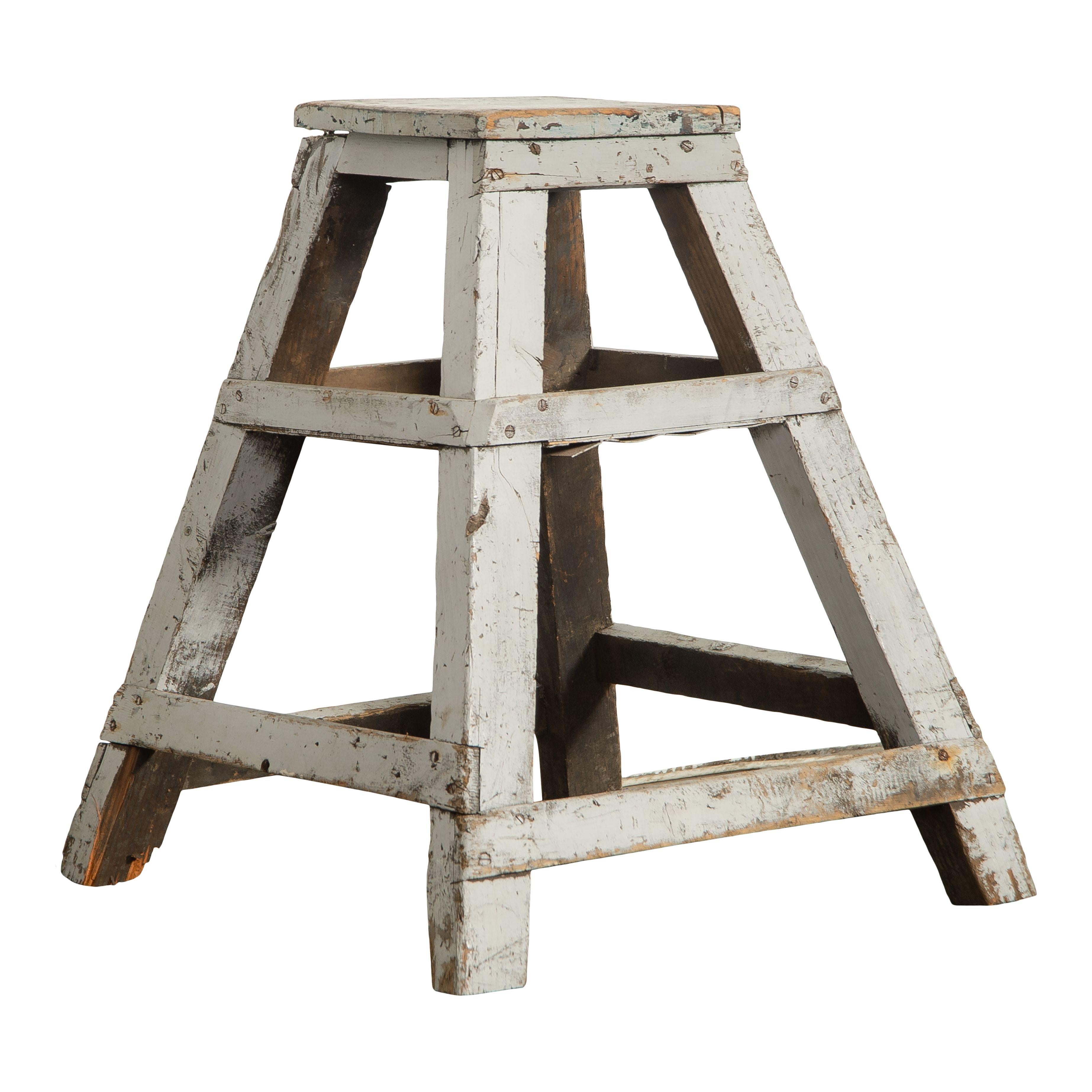 A lovely vintage sculpture stand made of wood and painted white. This piece features a classic and simple design with slanted legs, basic crosspieces, and a simple square top. The simple design and chipping paint makes this such a charming vintage