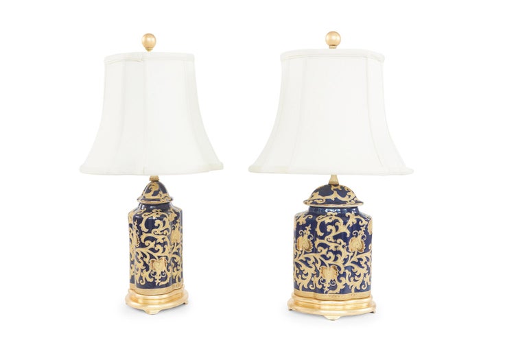 Late 20th century pair of gilt porcelain table lamps with gold leaf wooden base. Each lamp is in excellent working condition. Rewired for US use . From base to finial each lamp stands about 24 inches high x 8 inches diameter . Each lamp comes with a