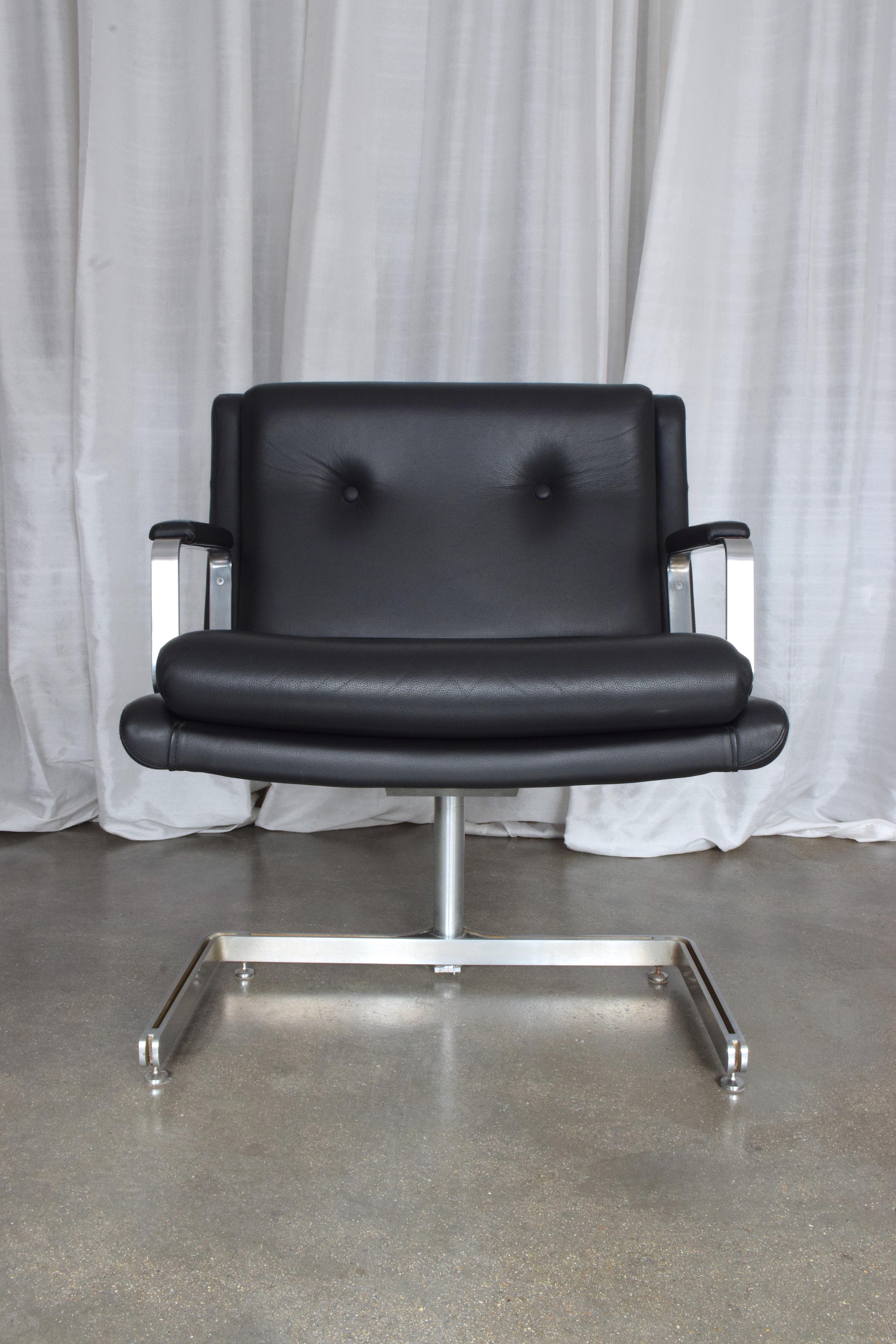 A set of two highly collectible vintage lounge or office chairs by iconic French designer Raphael Raffel designed in stainless steel and black leather with its distinctive tripod shaped structure. 
We have included two images of the book in which