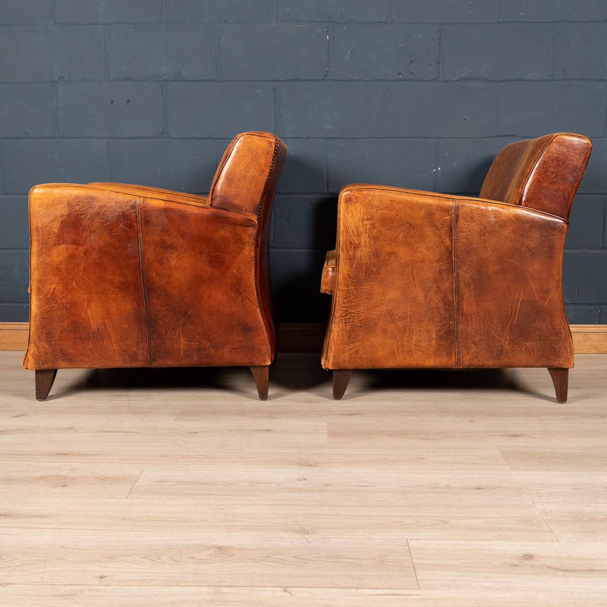 Showing superb patina and colour, this wonderful pair of club chairs were hand upholstered sheepskin leather in Holland by the finest craftsmen. An unusual Art Deco style model and of excellent quality. Fantastic look for any interior, both modern