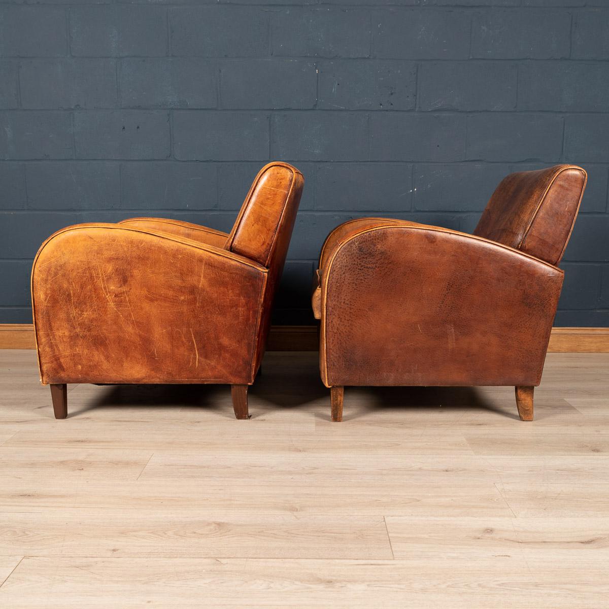 Showing superb patina and colour, this wonderful pair of club chairs were hand upholstered sheepskin leather in Holland by the finest craftsmen. An unusual Art Deco style model and of excellent quality. Fantastic look for any interior, both modern