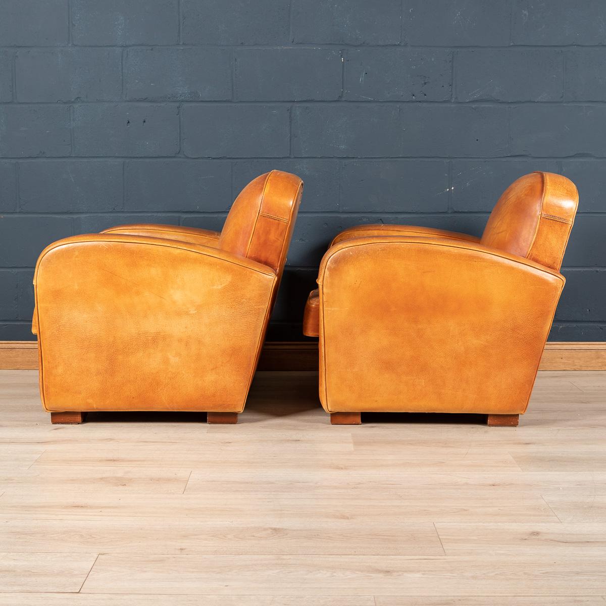 Gorgeous pair of Art Deco French leather club chairs, late 20th century. Wonderful and unusual shape and model, structurally sound, these chairs perennially ooze class and sophistication. Extremely comfortable, they suit any style of