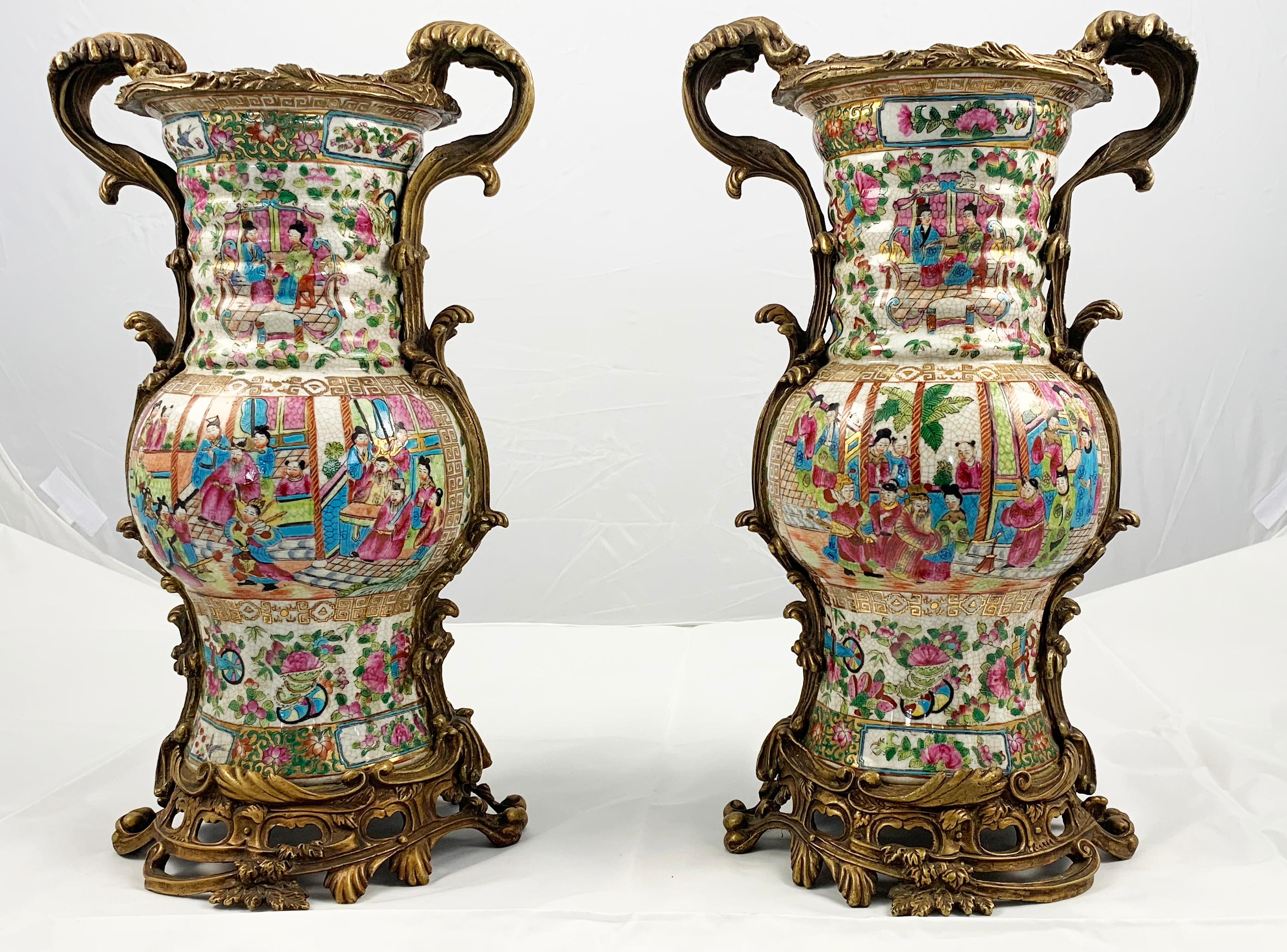 A pair of late 20th century Famille rose Cantonese ormolu-mounted vases. Of heavy baluster form with ribbed neck. Decorated throughout with figures interior scenes. The ormolu mounts cast in the form of scrolling foliage.