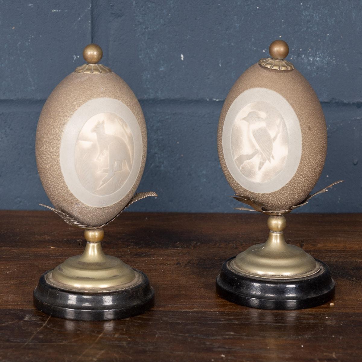 Antique 20th century extremely rare pair of Australian carved emu eggs, mounted on a nickel stand shaped as ferns and an ebonized wood base. These artifacts would have been primarily aimed at the tourist market as souvenirs for visitors and are