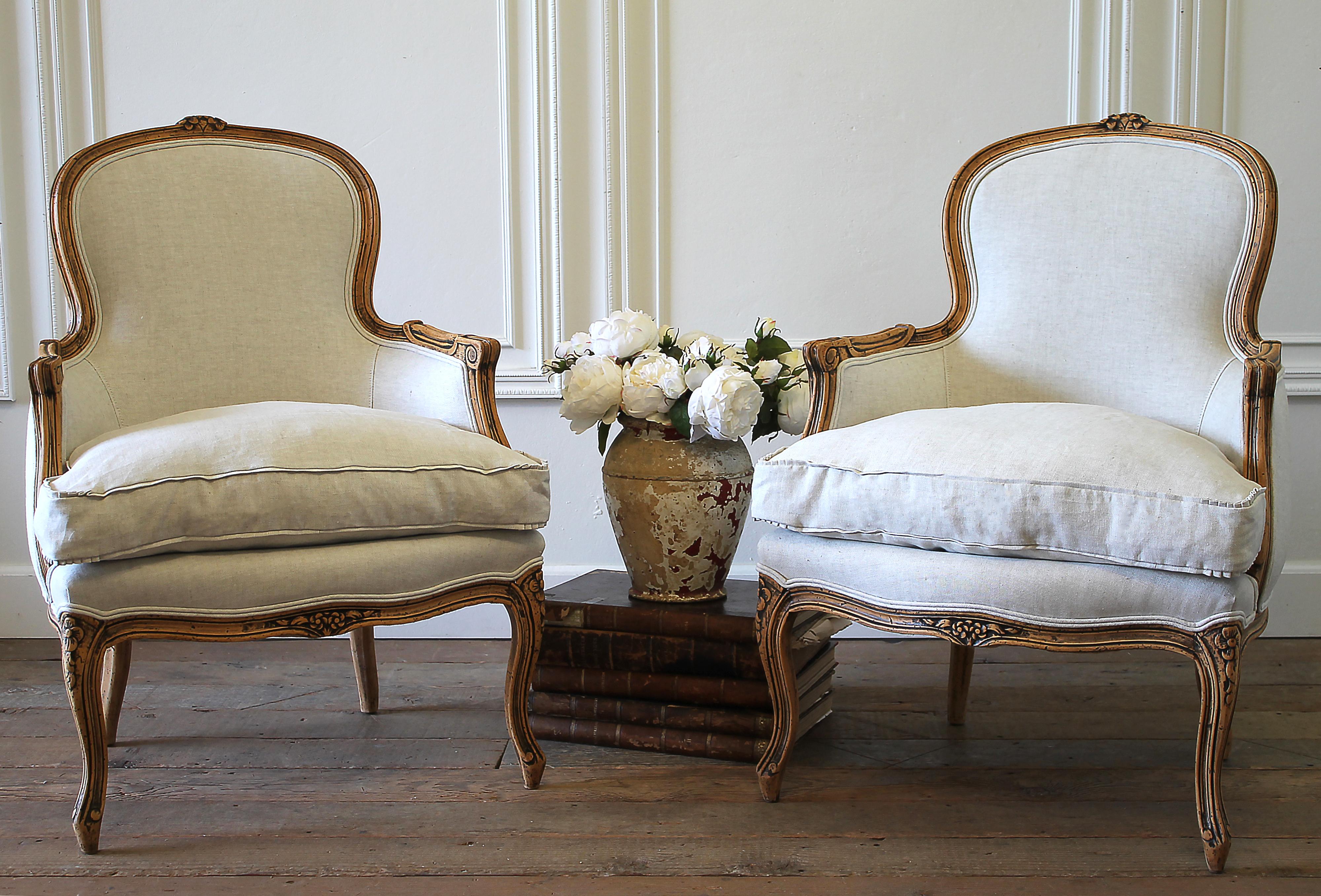 20th century carved and upholstered Louis XV style bergère chairs in linen.
These pair of chairs have a natural wood patina, almost best described as a raw wood, with beautiful patina. Carved Louis XV style, reupholstered in 100% pure Belgian