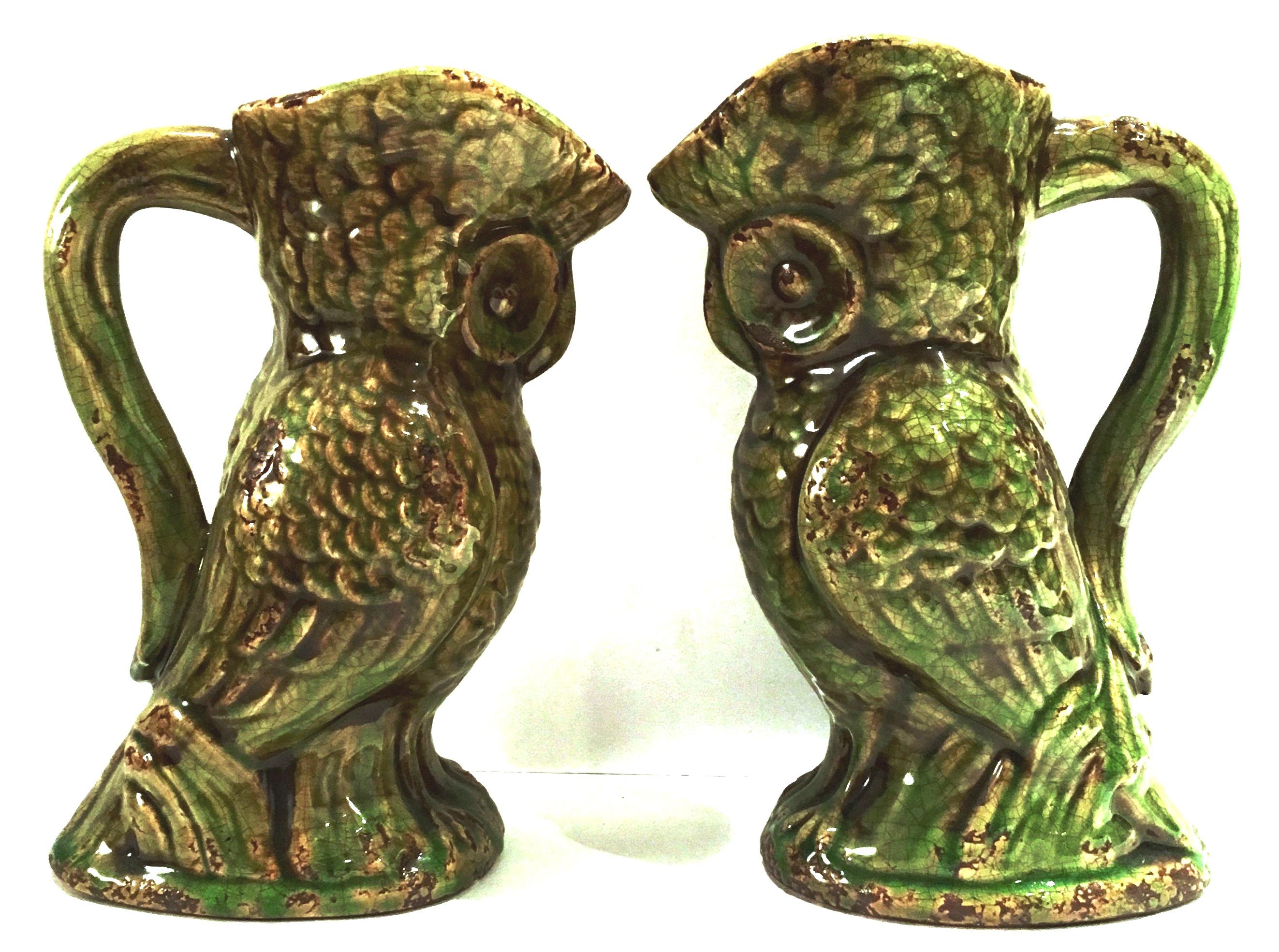 20th century pair of ceramic glaze handled owl beverage pitchers. Finished in a green and brown faux aged patina.
