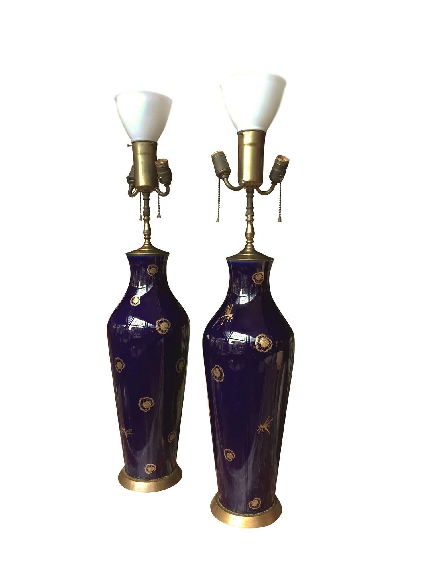 These stunning porcelain table lamps are attributed to Sèvres, a French factory specializing in porcelain, with royal beginnings. The lamps are rich cobalt blue with gilt-painted decorations of dragonflies and waterlilies adorning the glazed surface