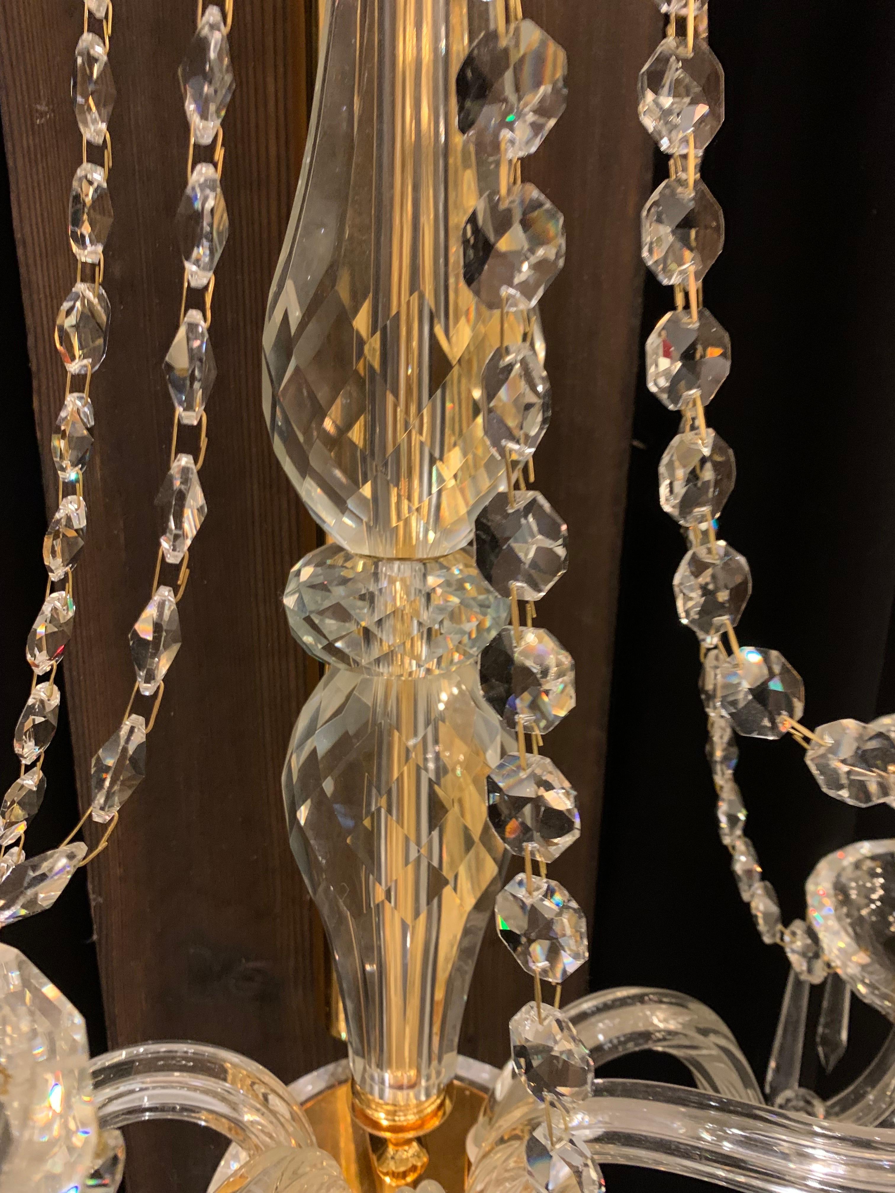 This pair of crystal wall lamp with 5 lights is made of solid and hand cut crystal. 
The central barrel is in gold metal covered by crystal parts.

We have 3 pair of this wall lamp in stock however we can produce them made to measure and in other