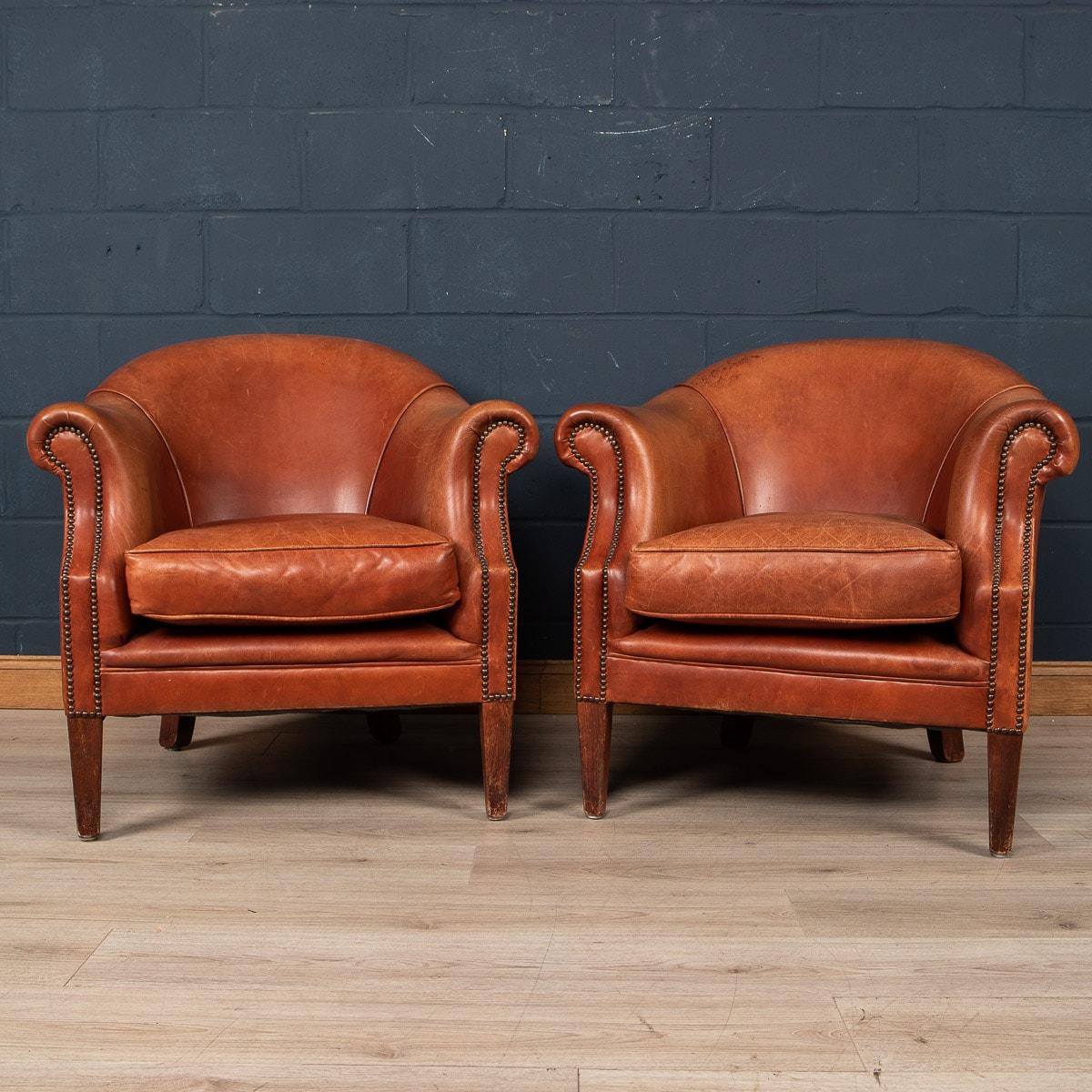 A wonderful pair of leather wing back armchairs. Dating to the latter part of the 20th century these chairs have been realised by the finest Dutch craftsmen, the solid wood frame upholstered in superb quality honey coloured sheepskin leather which