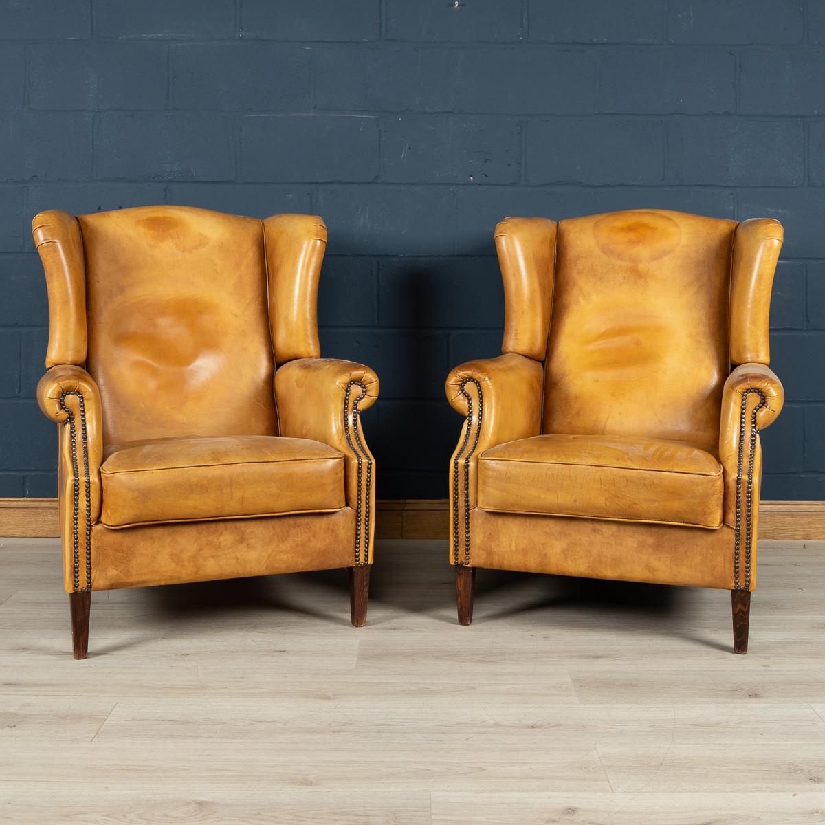 A wonderful pair of leather wing back armchairs. Dating to the latter part of the 20th century these chairs were realised by the finest Dutch craftsmen, the solid wood frame upholstered in superb quality sheepskin leather which over the years have