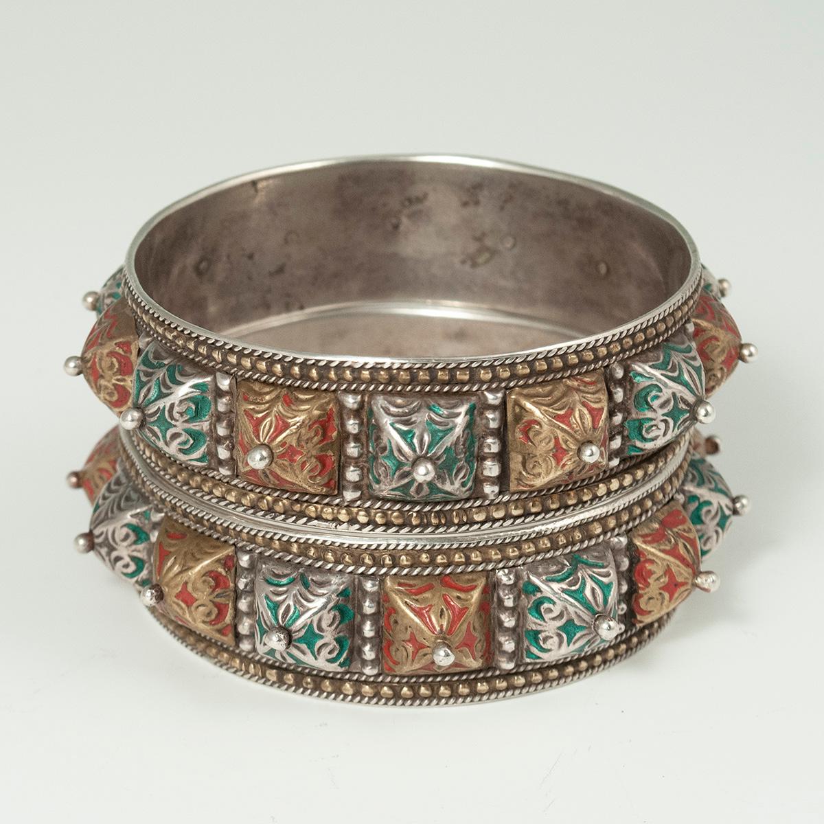 20th century pair of enamel and silver bracelets, Morocco

A beautiful pair of enamel and silver bracelets from Morocco. There may be a little gilding on the red enameled pyramidal bumps and on the raised dots along the edges.
The inner