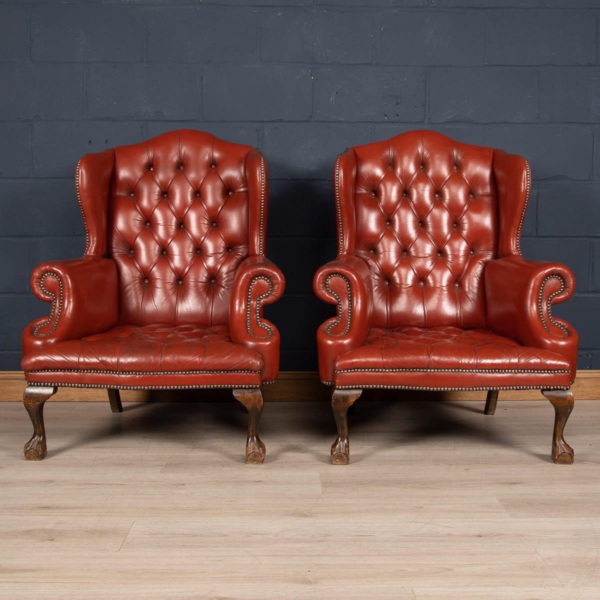 A truly stunning example of English leather craftsmanship, these leather wingback armchairs have an exceptionally rare studded seating and headrest, with brass studs on the armrest. The beautiful color and patina of the leather adds to the warm