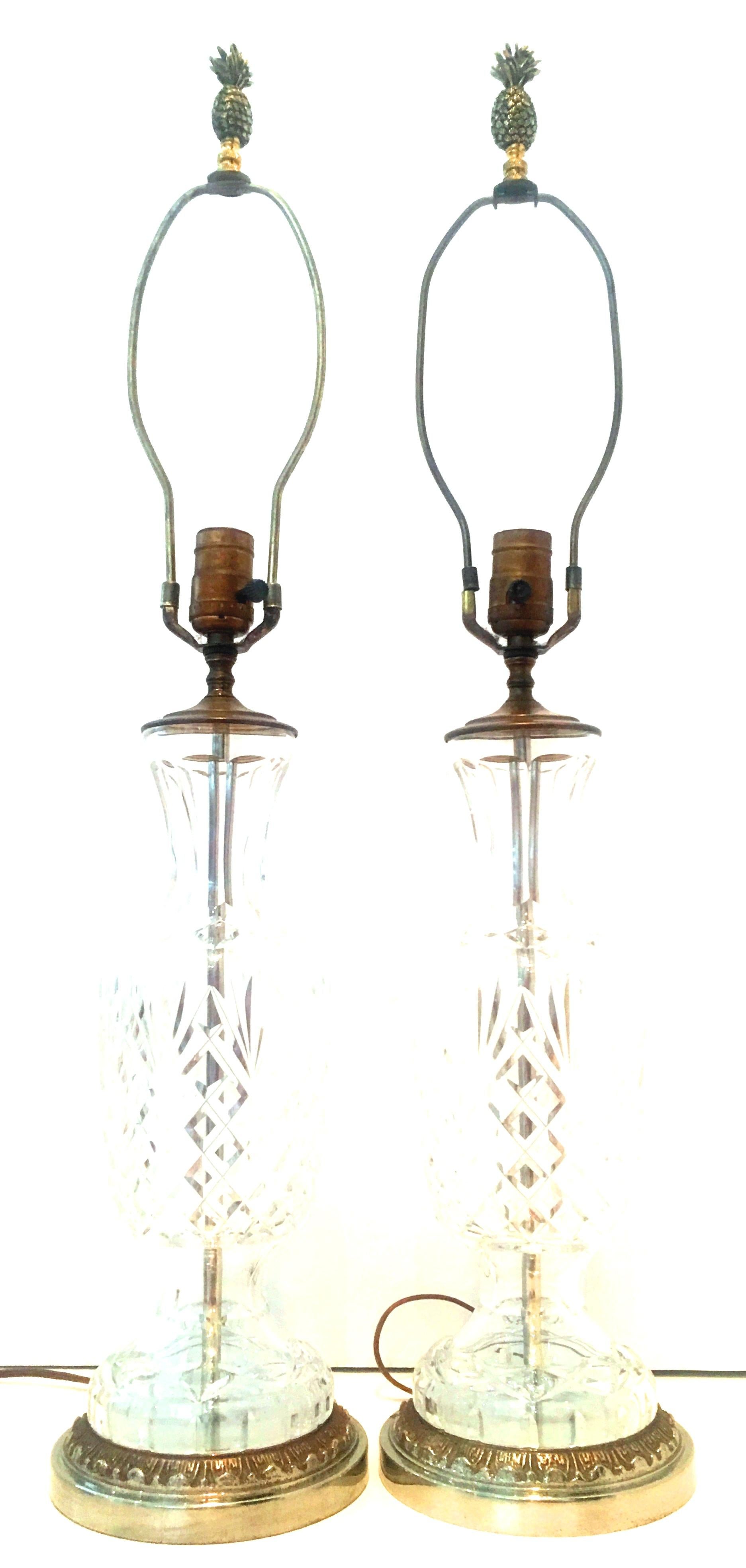 20th century pair of French cut crystal and polished brass table lamps. Features a diamond cut pattern, original solid brass fittings, new solid brass pineapple form finials and patina silver chrome base. Wired for the US and in working order.