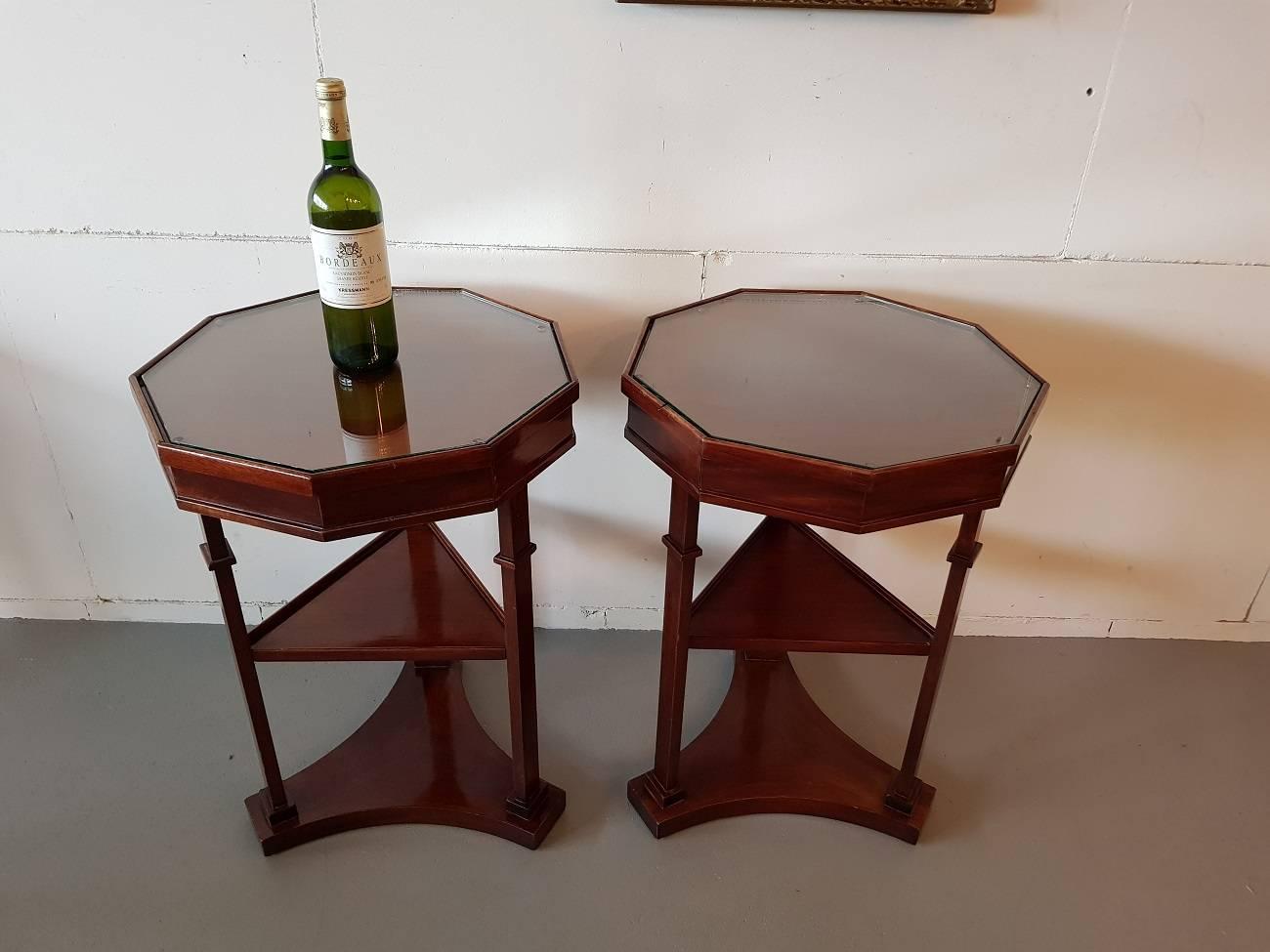 Set of two identical French nonagon shaped mahogany side tables in a classic design both with a glass plate and drawer. They were made at the end of the 20th century and wear consistent by age and use.

The measurements are,
Depth 49 cm/ 19.2