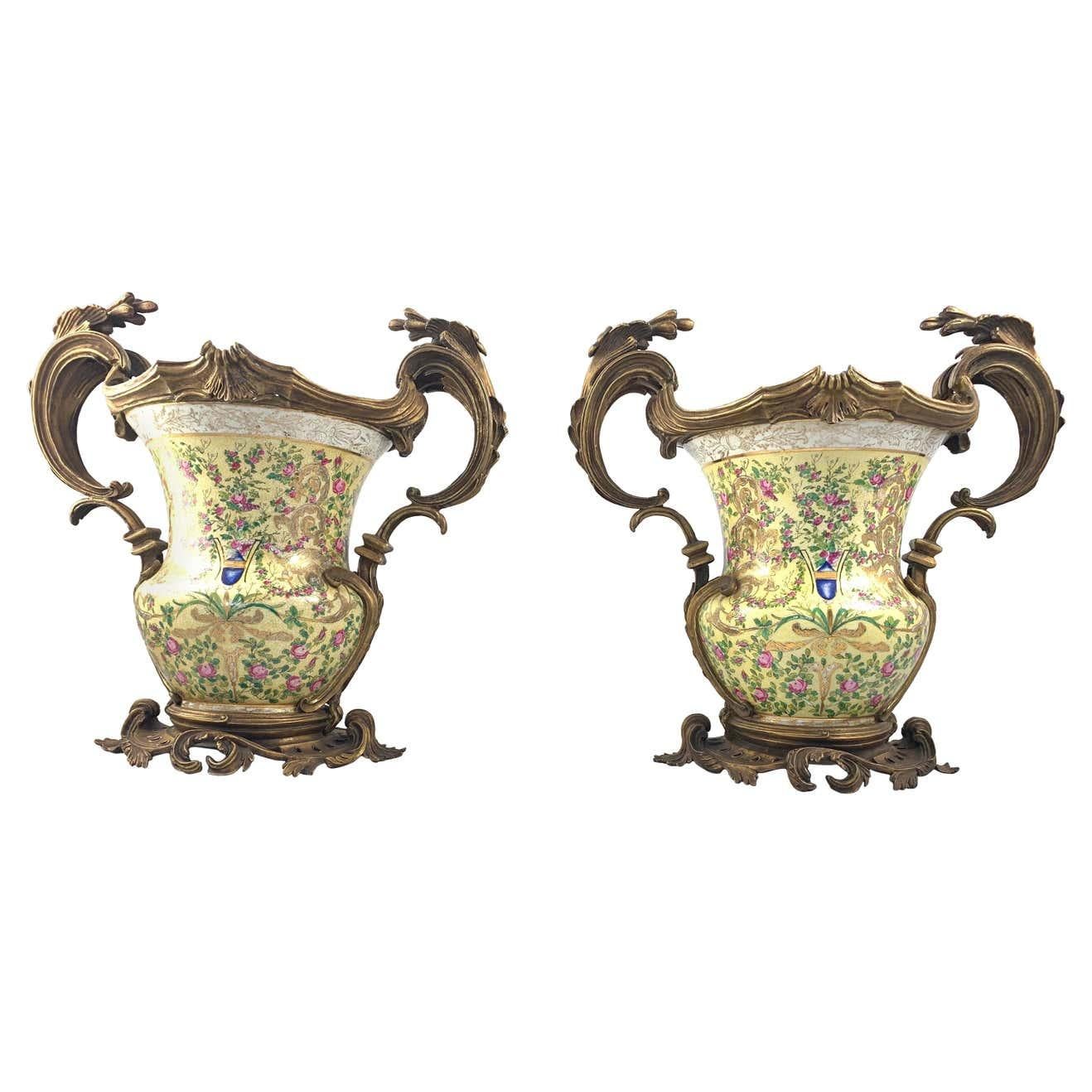 A fine pair of French porcelain and ormolu-mounted twin handled urns. Each heavy baluster body decorated with a coat of arms amongst flowers and foliage. The mounts conforming in design and supported by an impressive scroll cast base.