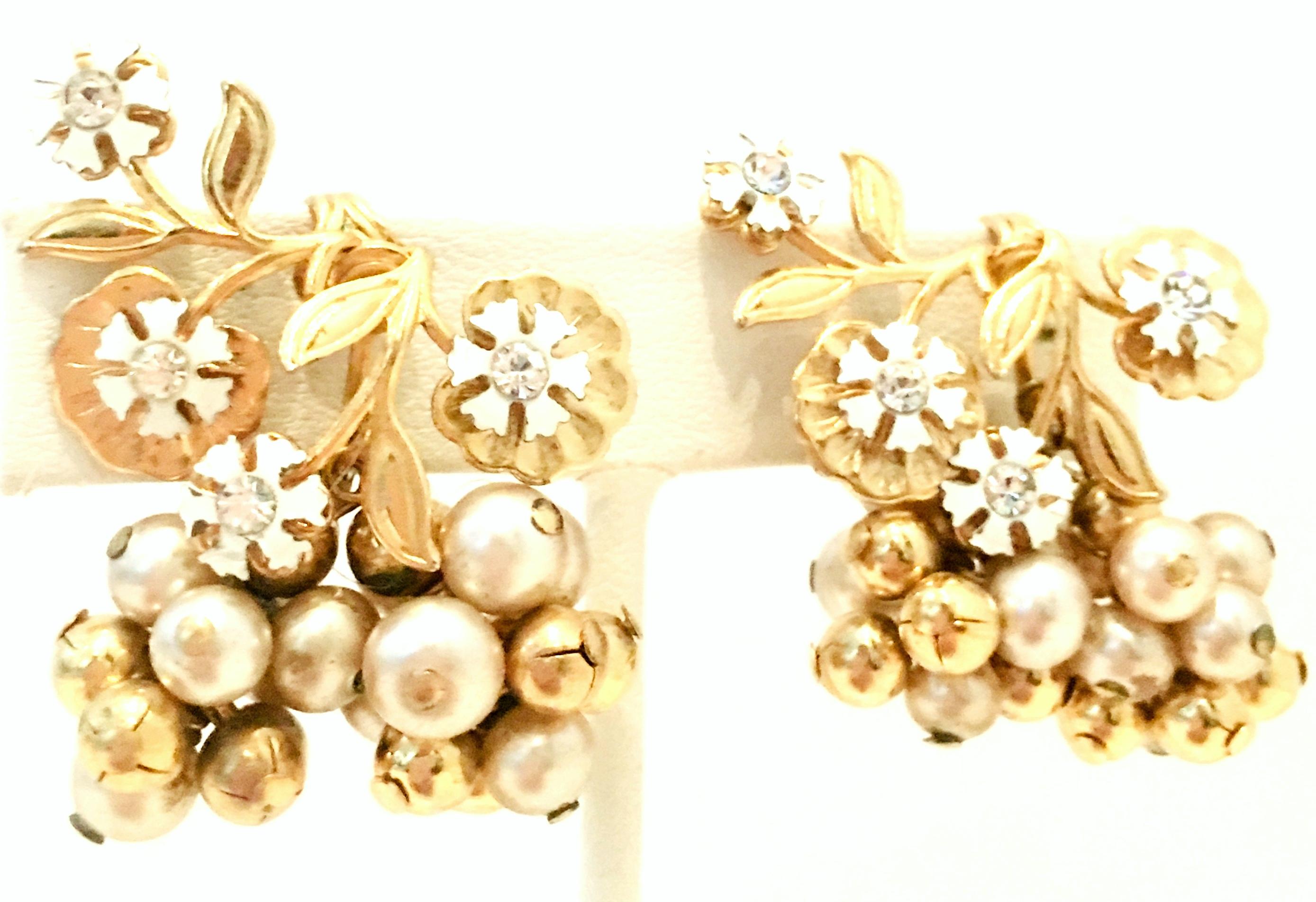 20th Century Pair Of Gold, Enamel, Austrian Crystal & Faux Pearl Dangle Earrings. These unique clip style dangle earrings feature gold plate metal with white enamel flowers, colorless Austrian crystal stones and faux pearl beads. The faux pearls are