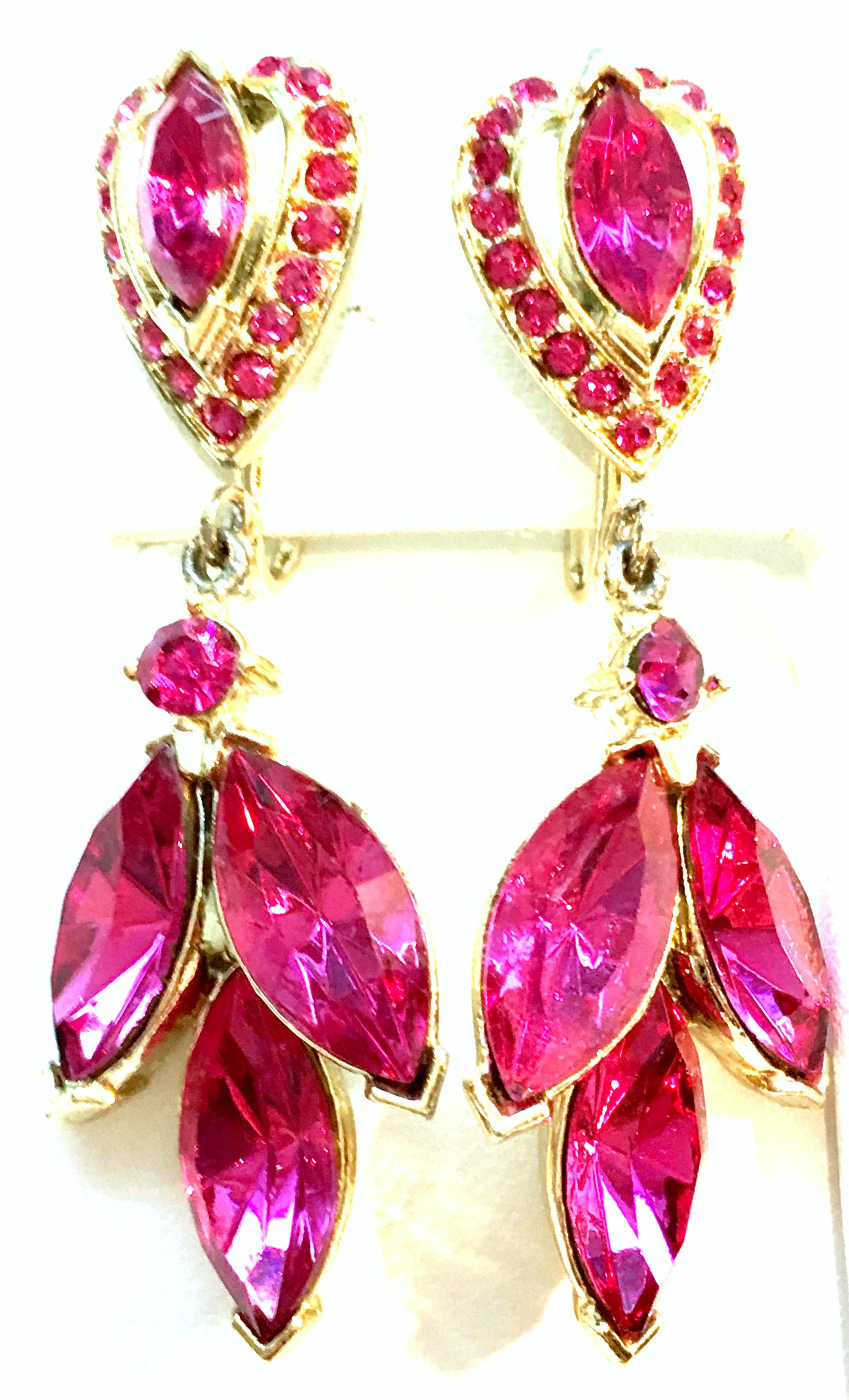 20th Century Pair Of Gold Plate & Swarovski Crystal Drop Earrings. These finely crafted clip style drop earrings feature gold plate with fancy prong set faux pink sapphire Swarovski crystal stones. There is an abstract heart form at the post and